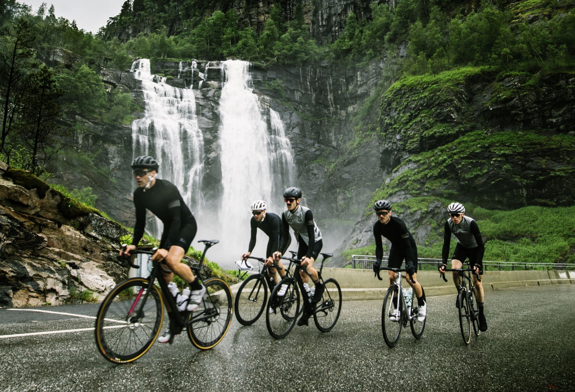 En grupp cyklister vid ett vattenfall i Fjord Norge