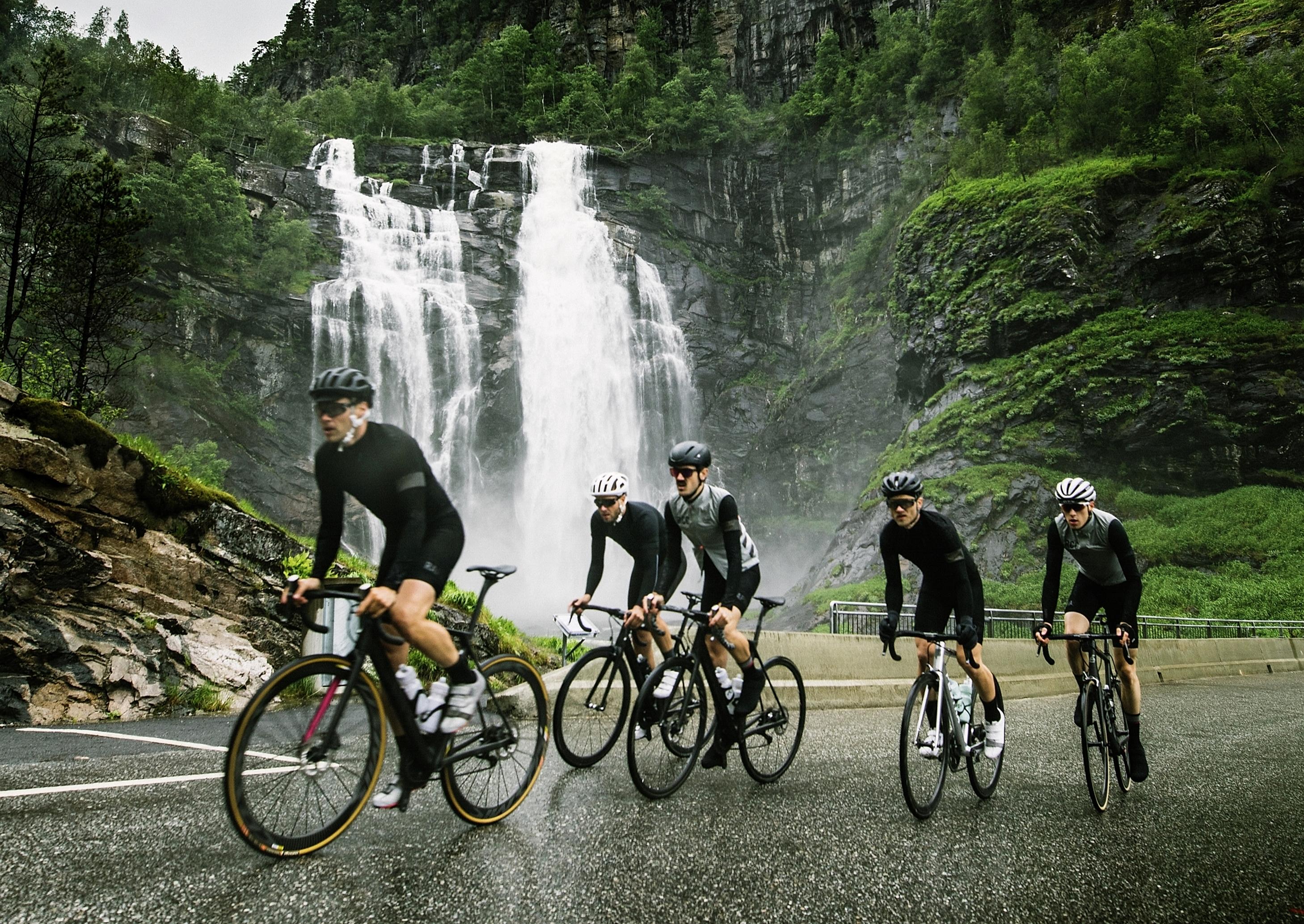 En grupp cyklister vid ett vattenfall i Fjord Norge