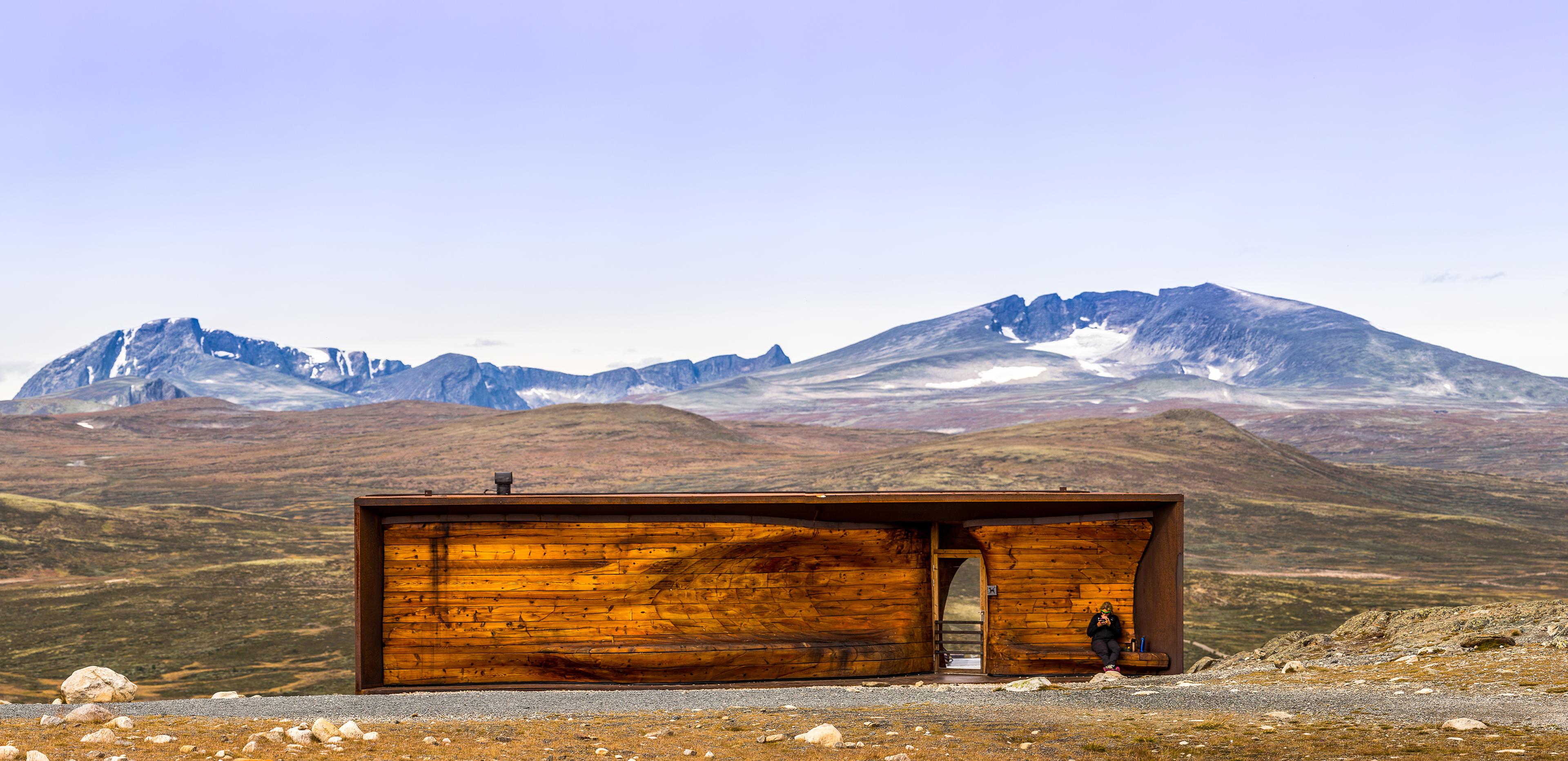 A person at the Viewpoint Snøhetta pavillion with the mountain Snøhetta in the background. Dovrefjell, Eastern Norway.