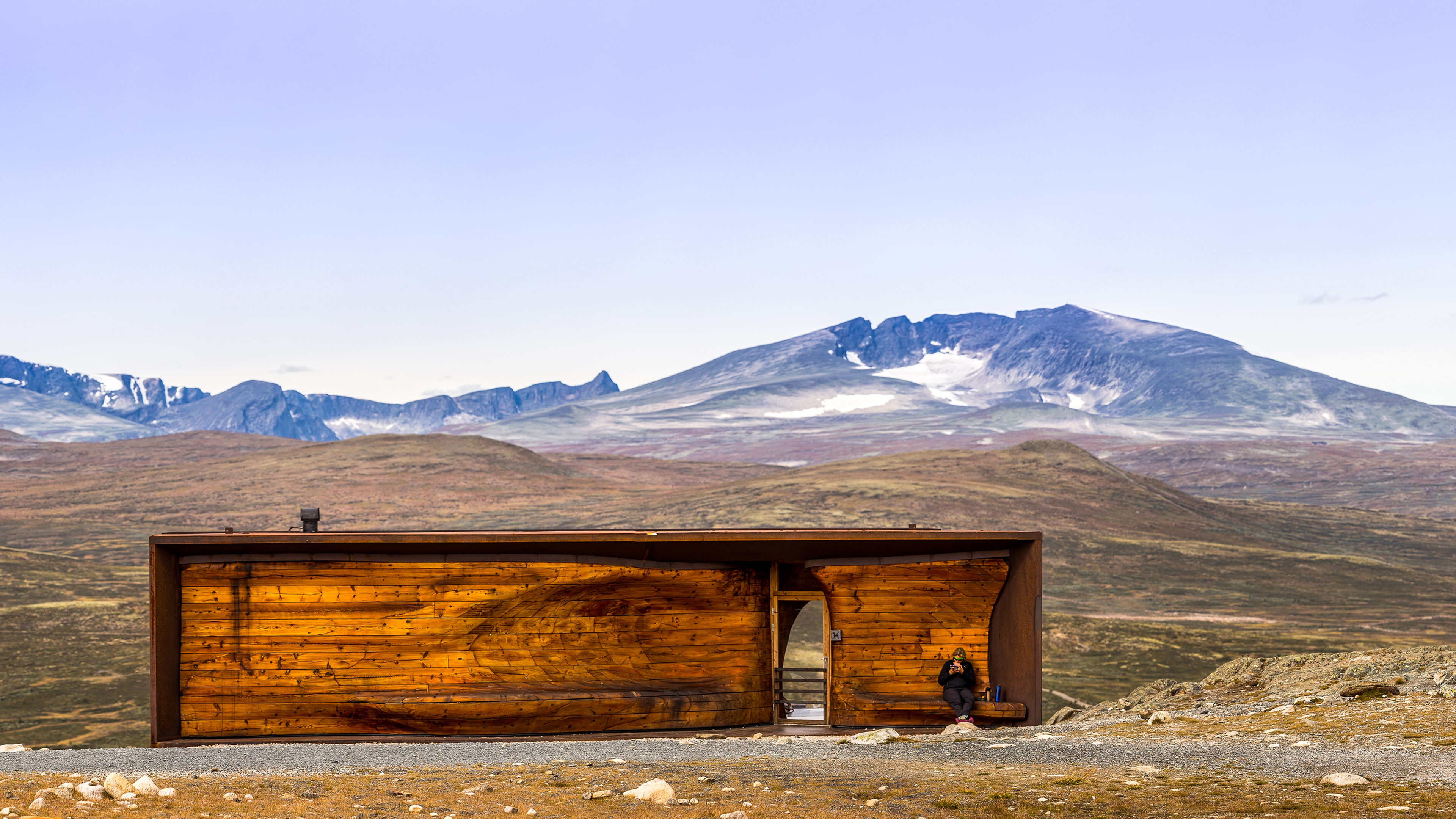 A person at the Viewpoint Snøhetta pavillion with the mountain Snøhetta in the background. Dovrefjell, Eastern Norway.