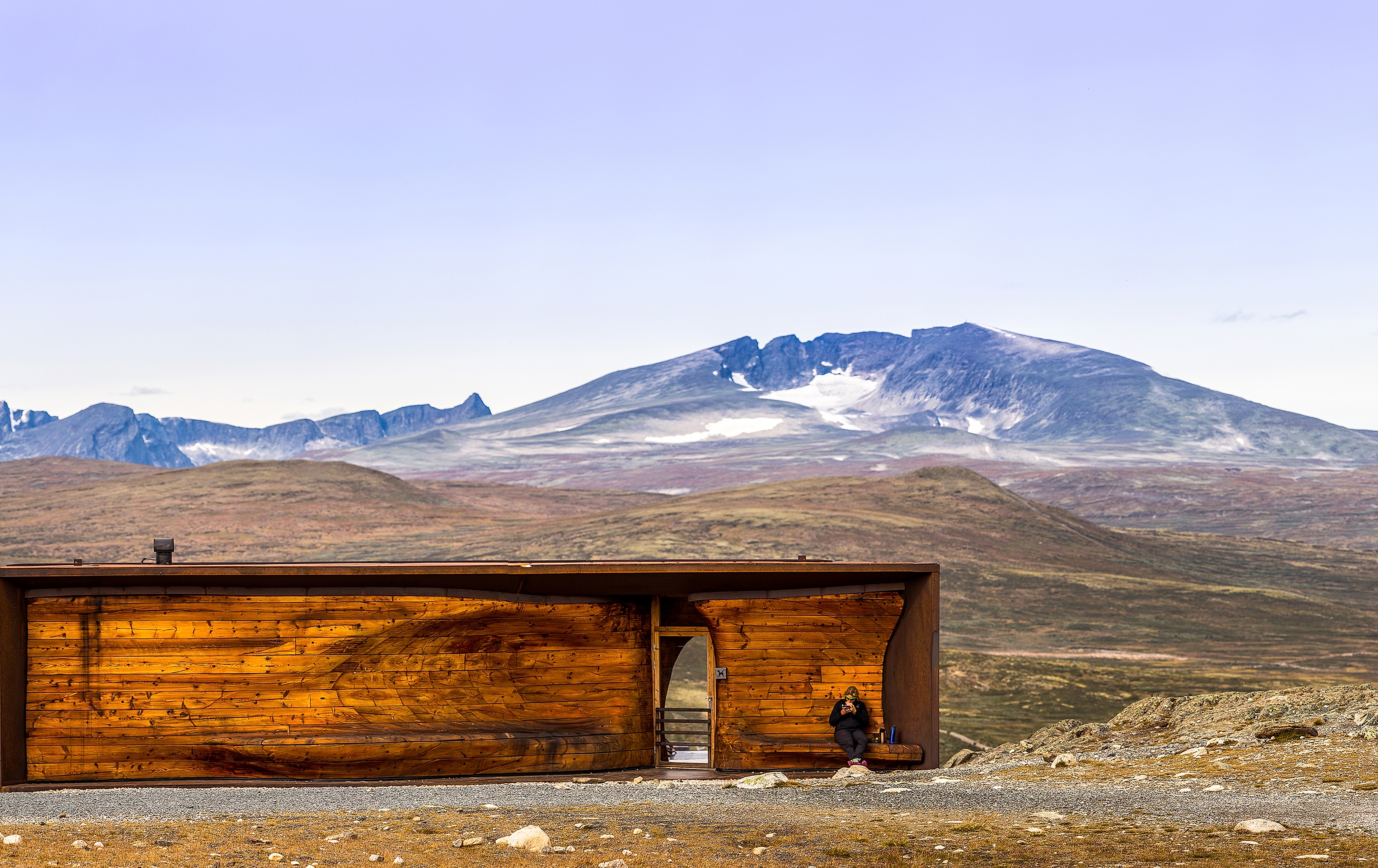 A person at the Viewpoint Snøhetta pavillion with the mountain Snøhetta in the background. Dovrefjell, Eastern Norway.