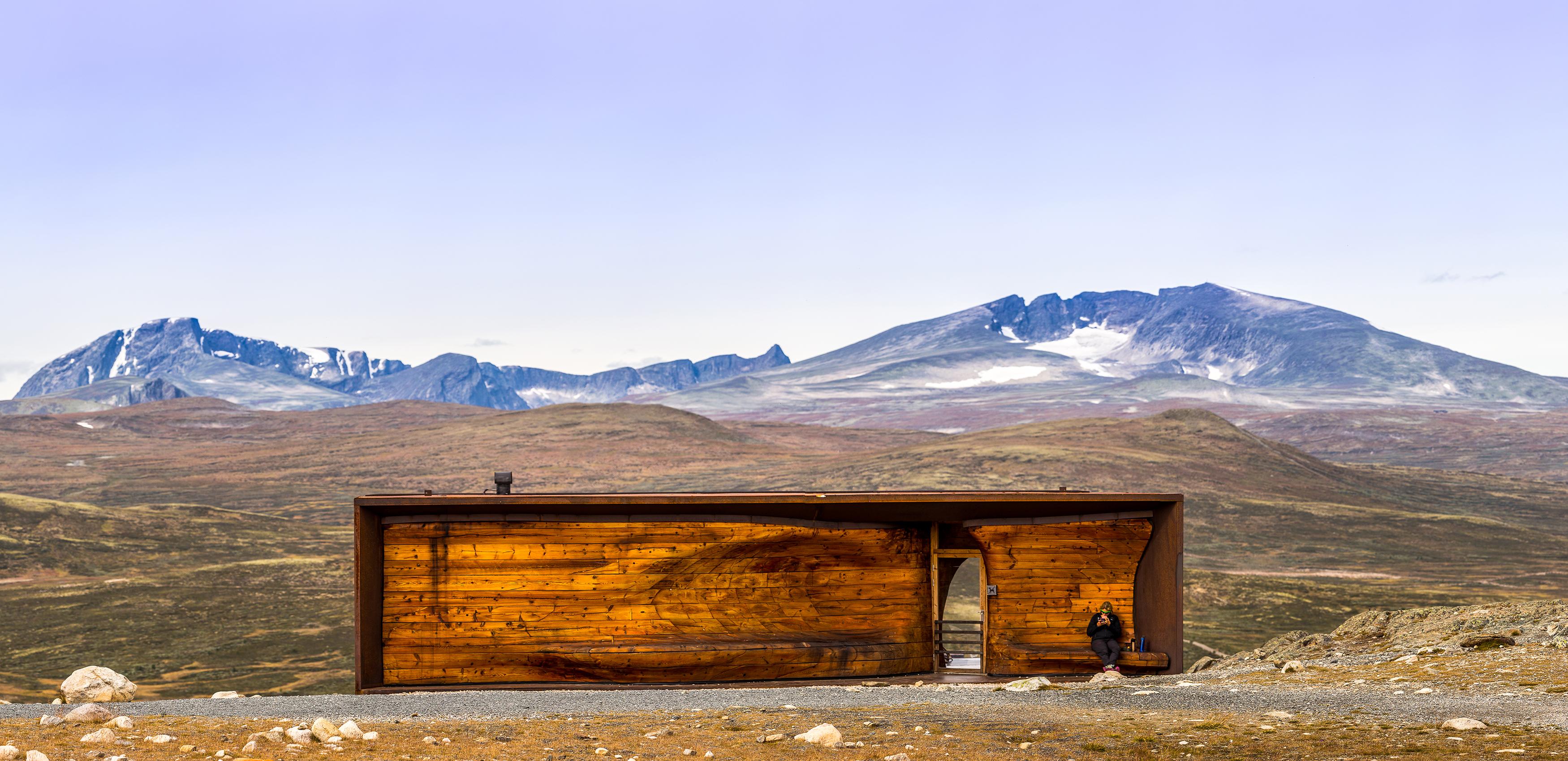 A person at the Viewpoint Snøhetta pavillion with the mountain Snøhetta in the background. Dovrefjell, Eastern Norway.