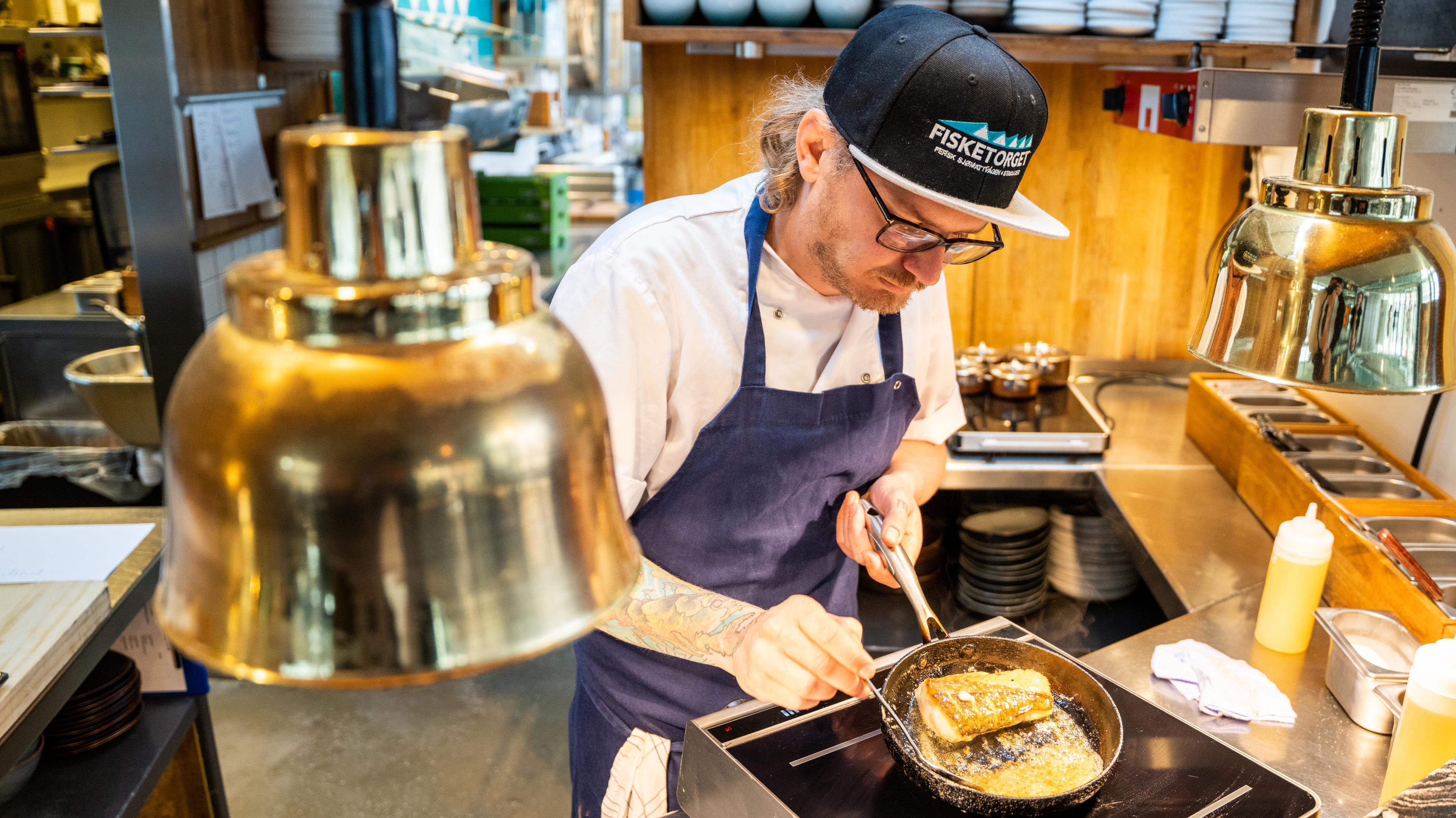 Karl Erik frying fish at Fisketorget restaurant in Stavanger, Fjord Norway.