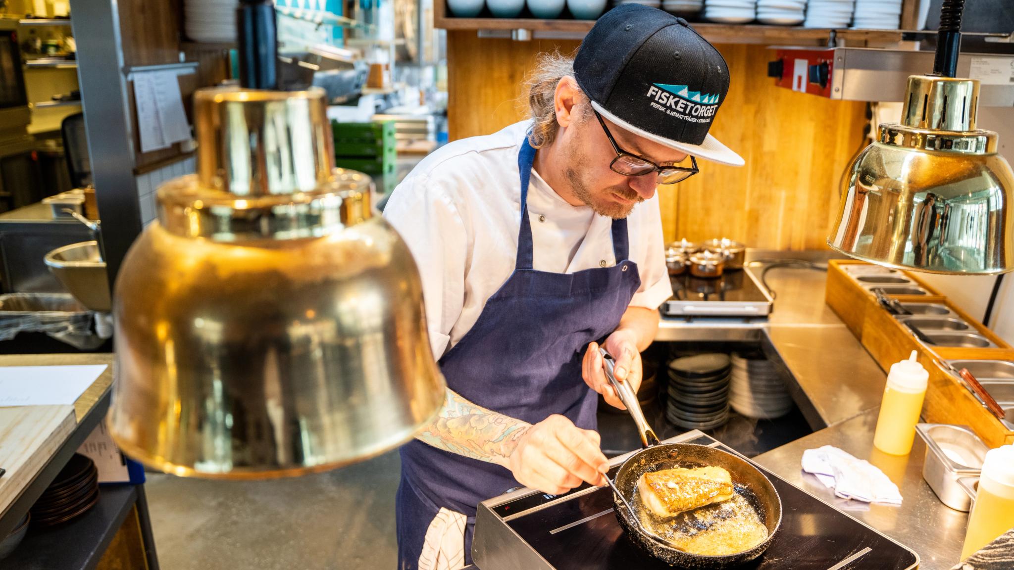 Karl Erik frying fish at Fisketorget restaurant in Stavanger, Fjord Norway.