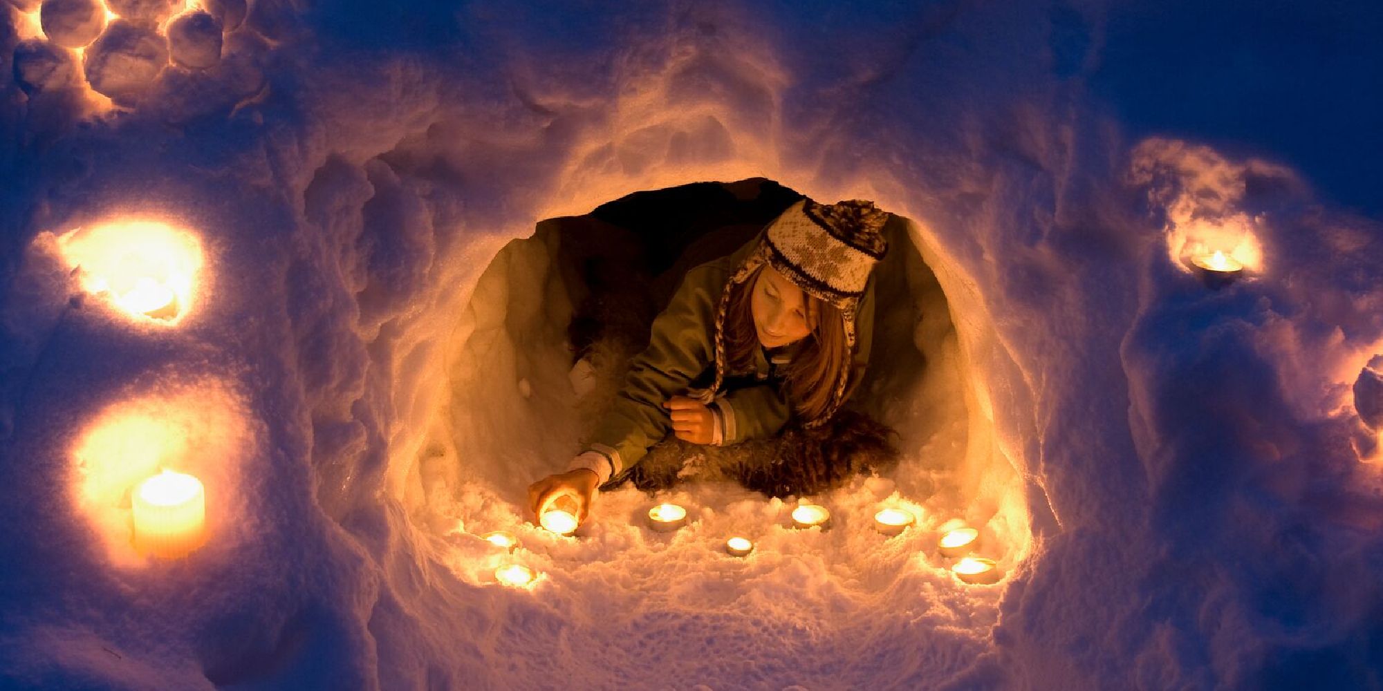A girl lights a candle in a snow igloo in Trysil in Eastern Norway