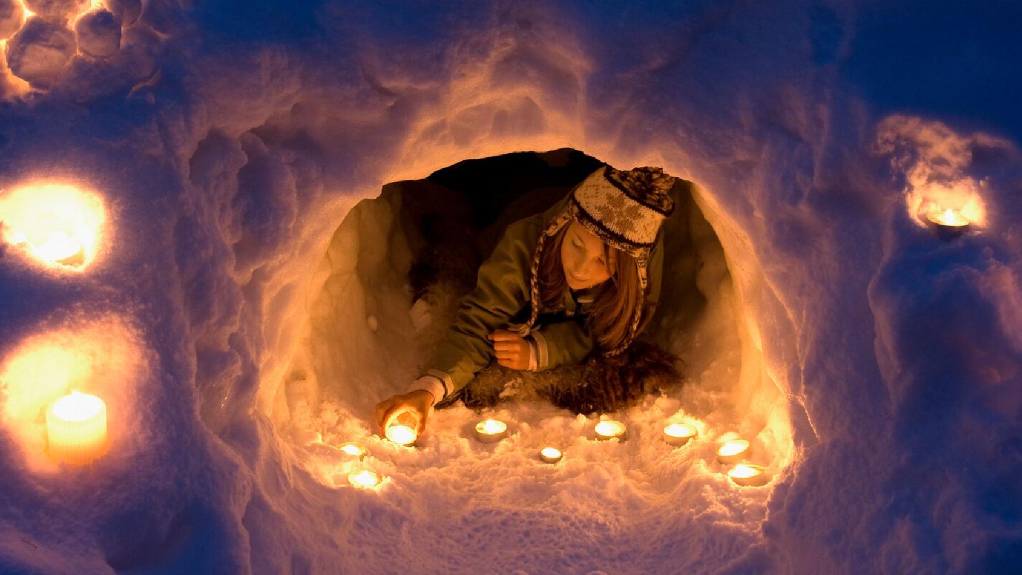 A girl lights a candle in a snow igloo in Trysil in Eastern Norway