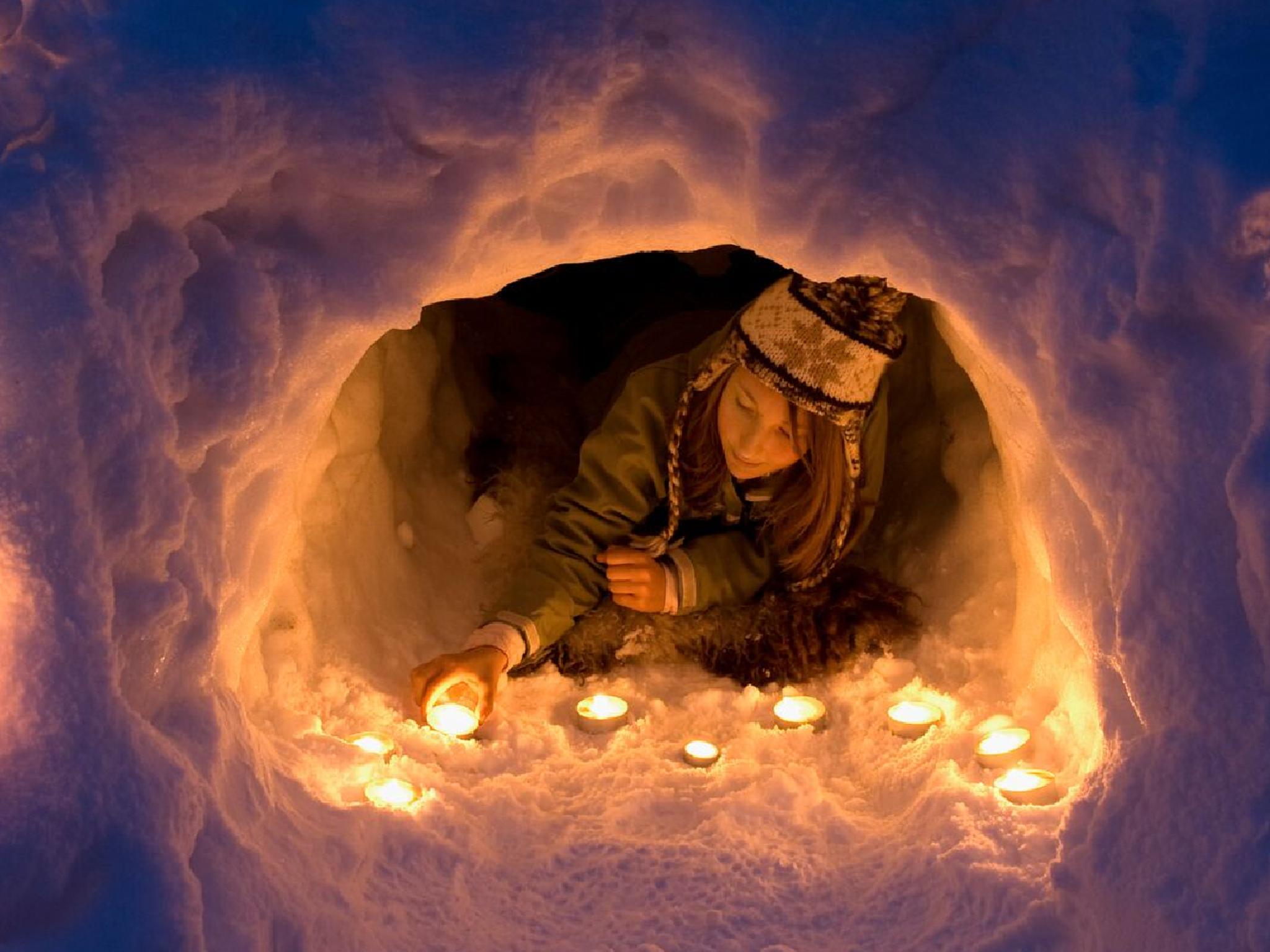 A girl lights a candle in a snow igloo in Trysil in Eastern Norway