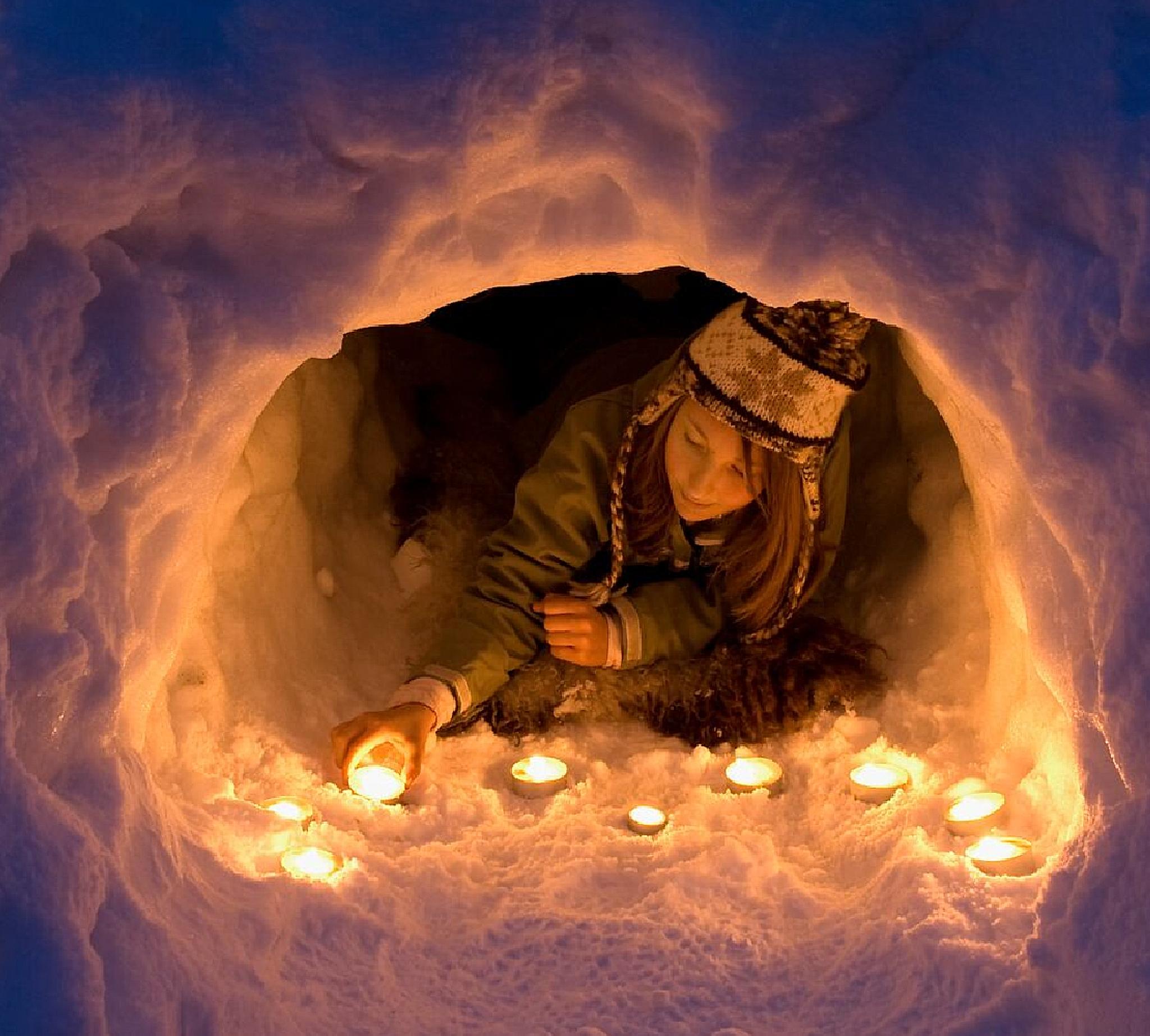 A girl lights a candle in a snow igloo in Trysil in Eastern Norway