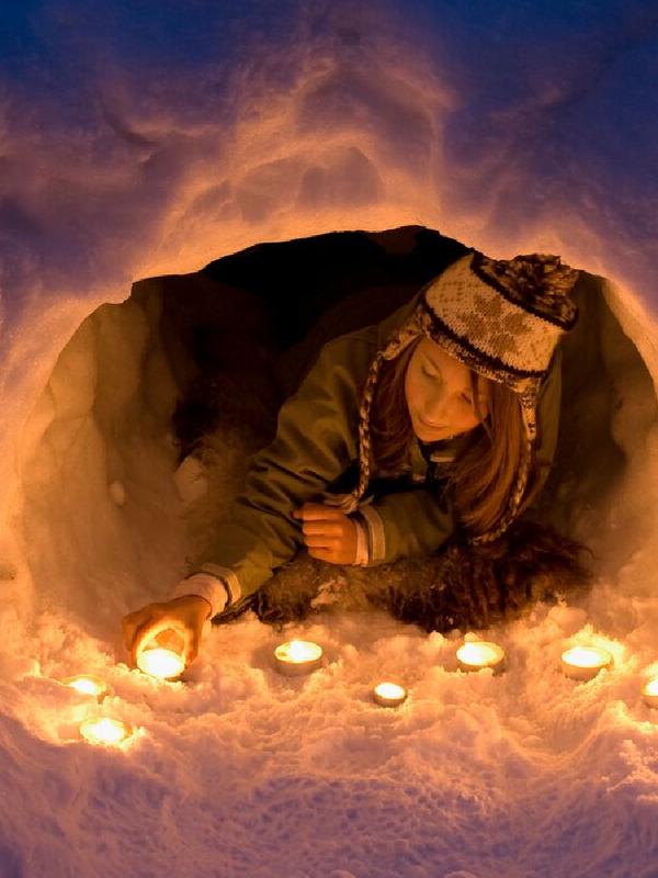A girl lights a candle in a snow igloo in Trysil in Eastern Norway