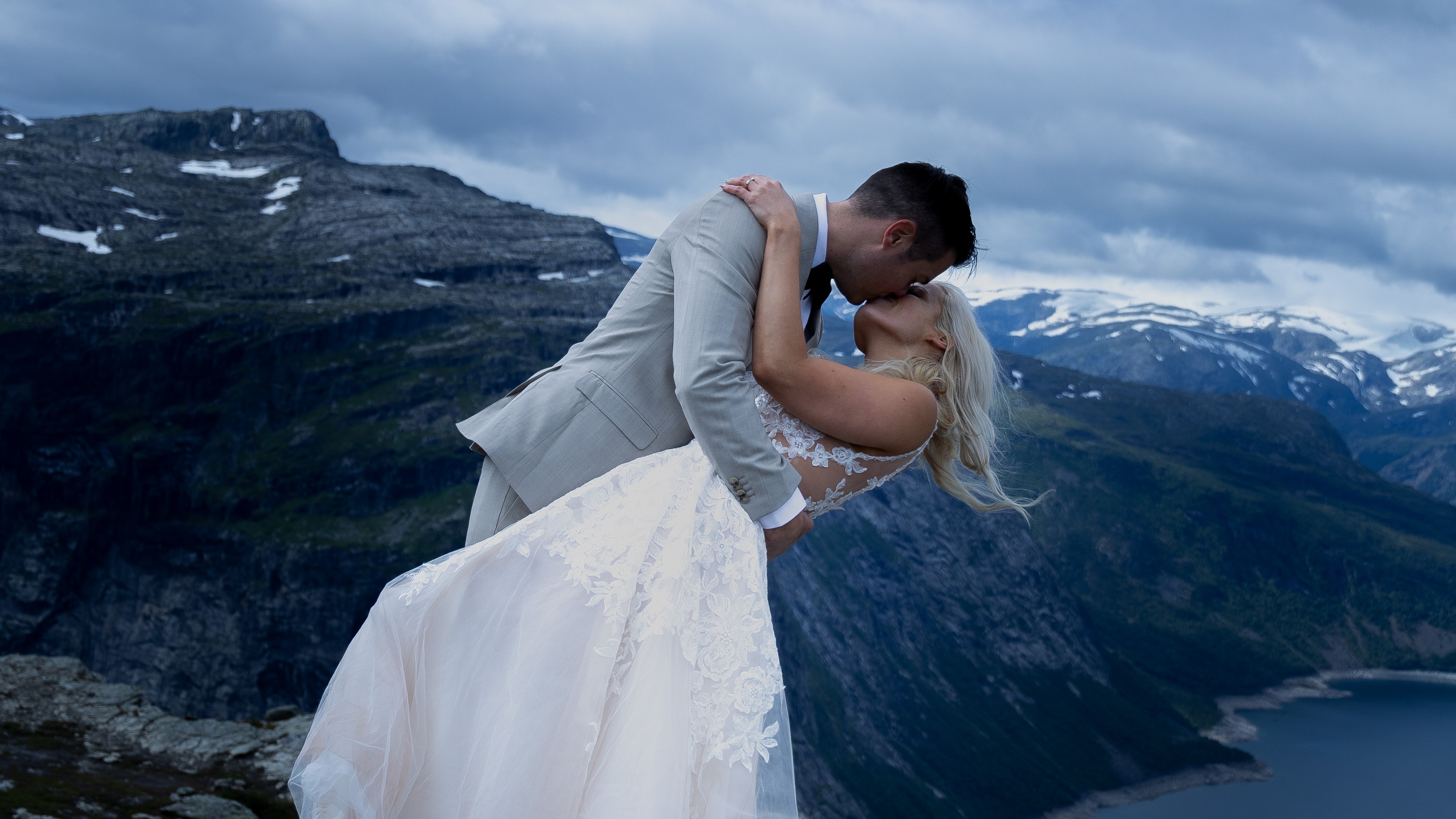 A newly wed couple kissing at the top of Trolltunga in Ullensvang in Fjord Norway