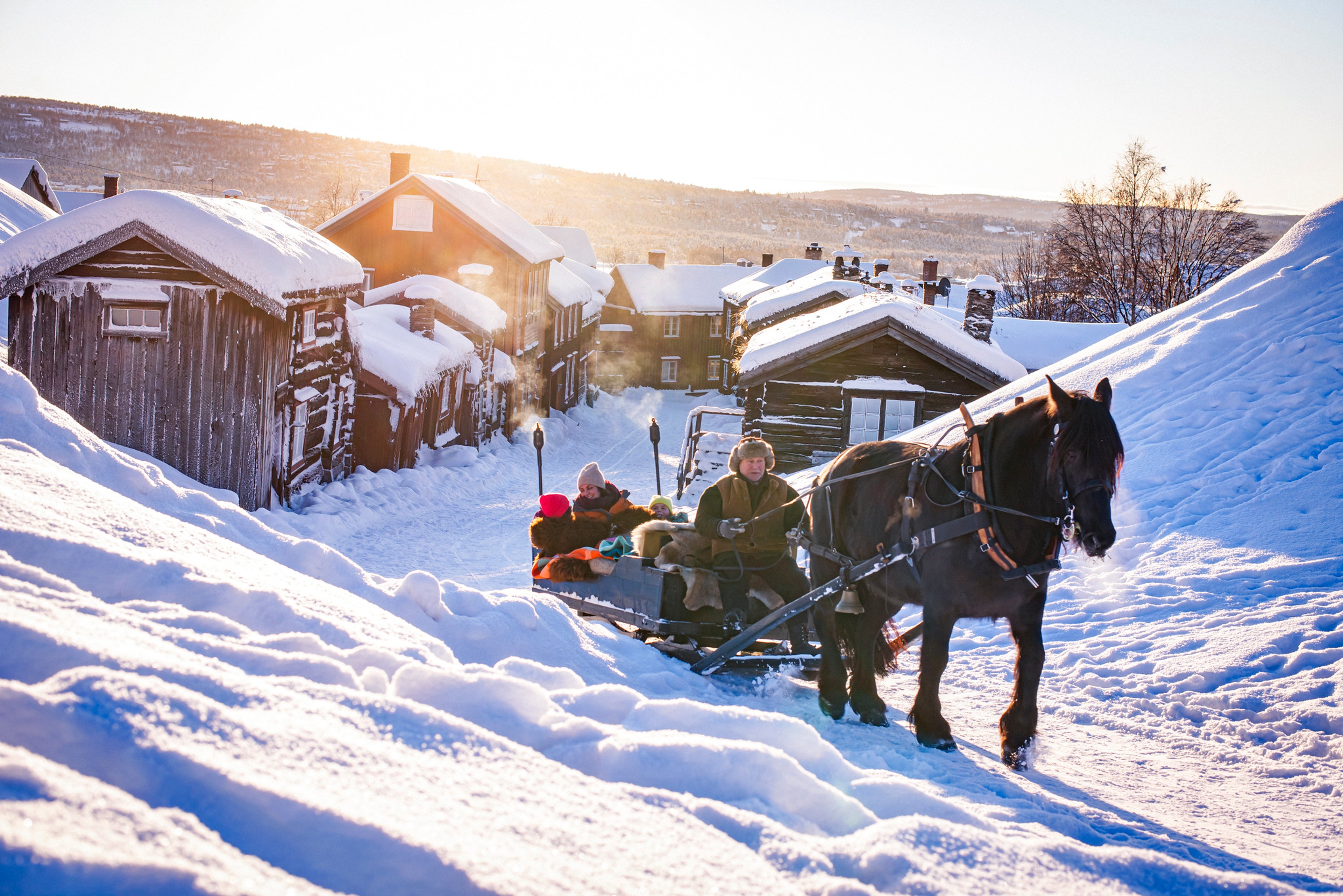 Three people riding a horse and sleigh at Røros a cold winter day
