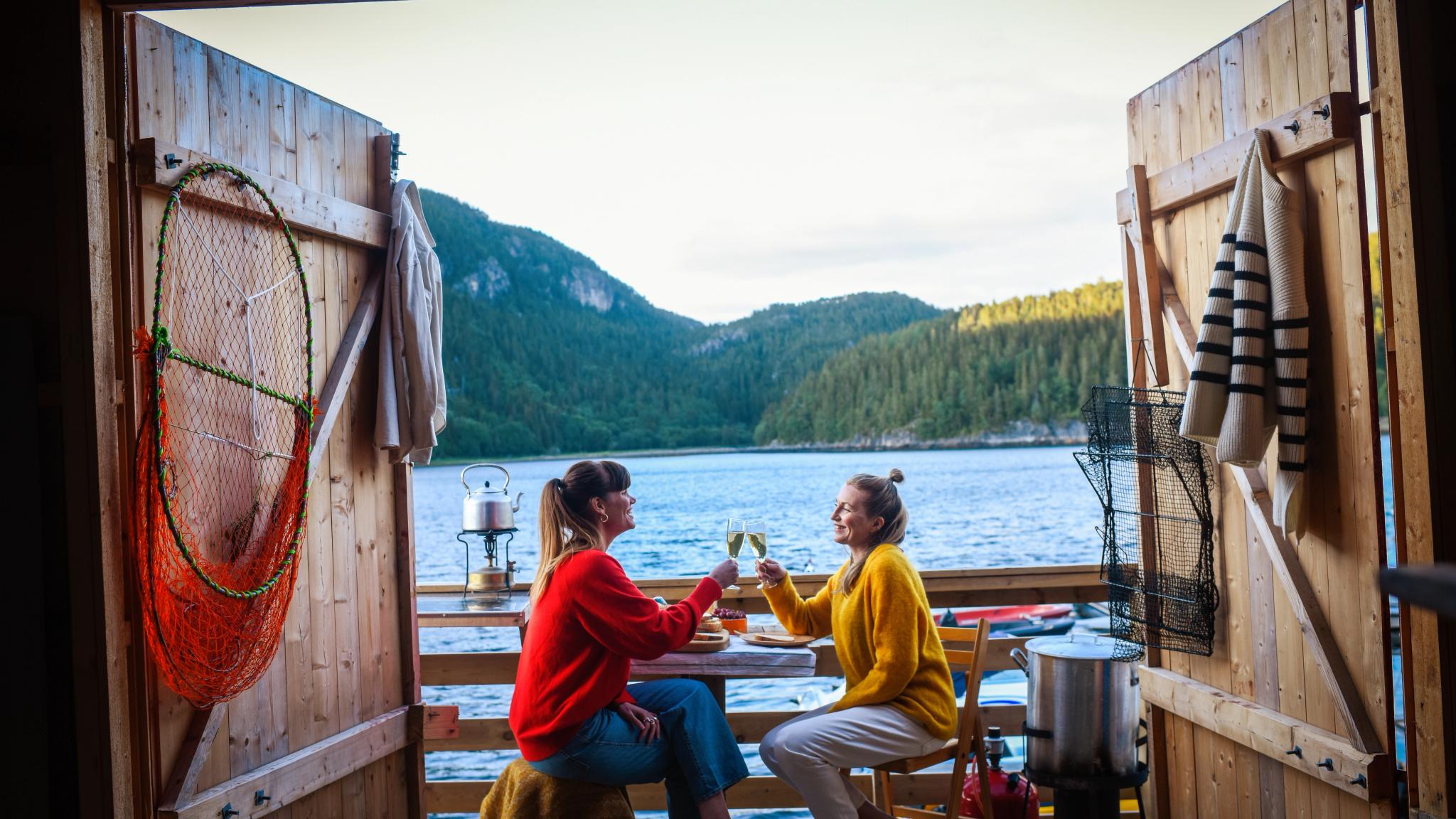 Two woman enjoying some drinks outside a fisherman's cabin by the sea