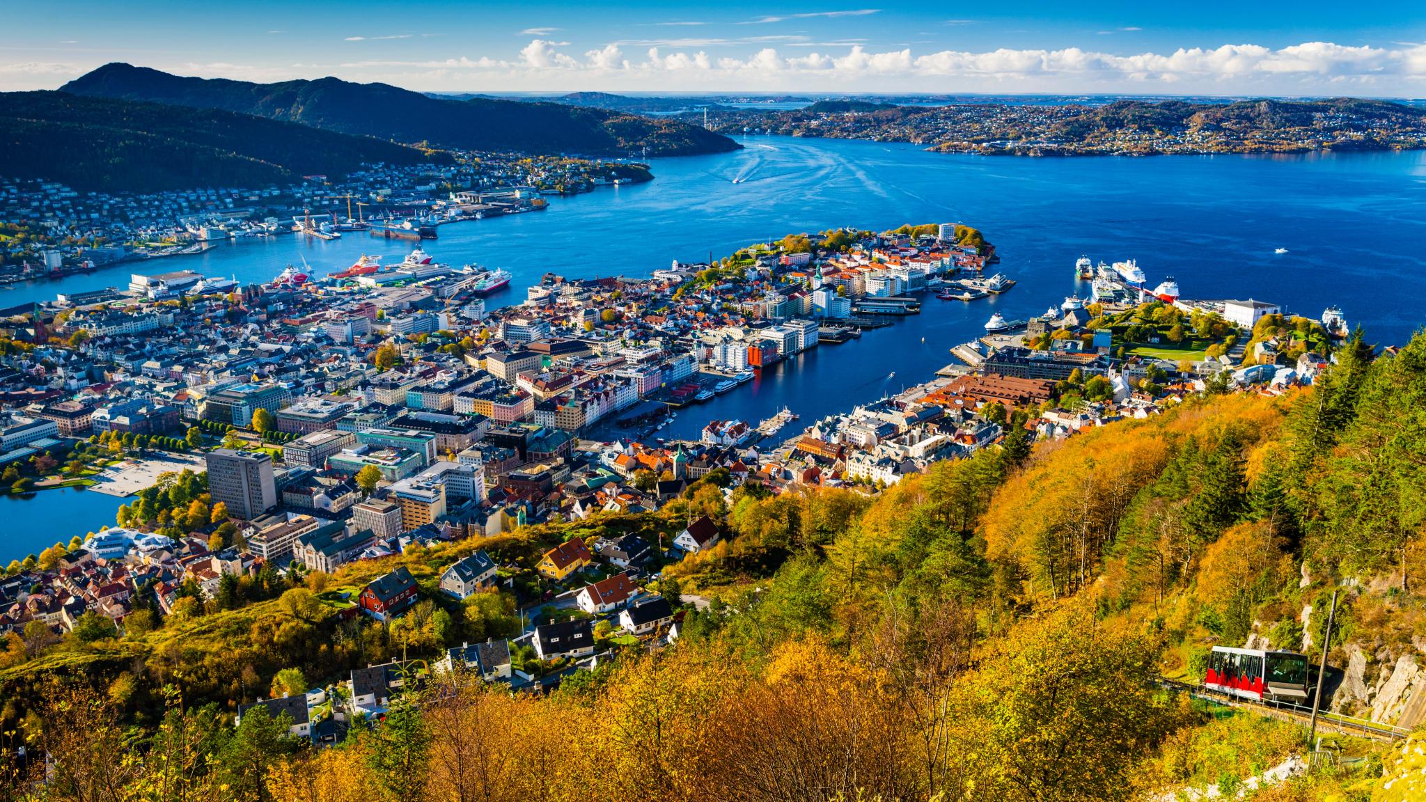 The Fløibanen funicular on its way up Mount Fløyen in Bergen, Fjord Norway, with a view of the city and the fjord