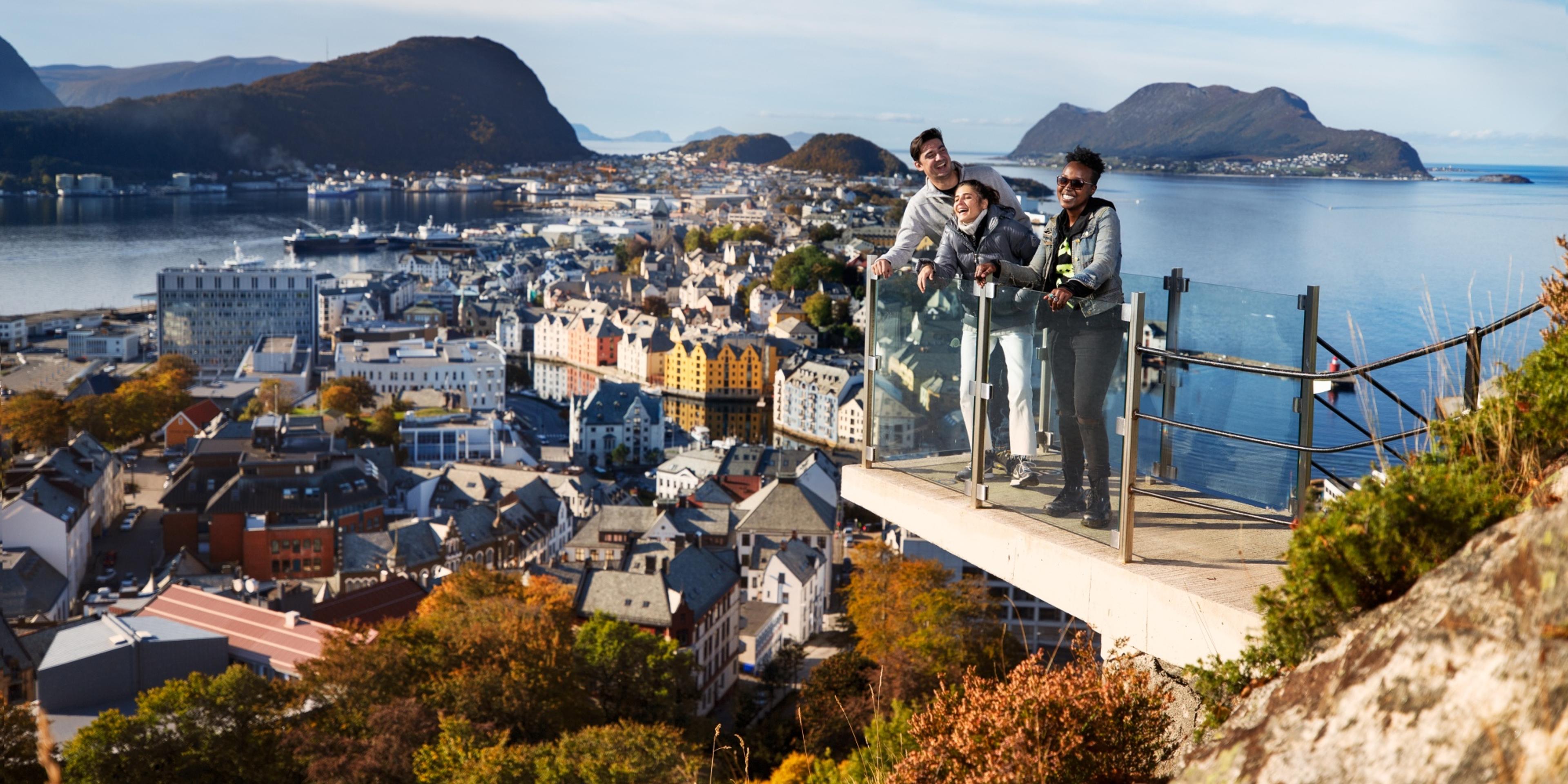 Three people standing at a viewpoint above the city of Ålesund in Fjord Norway