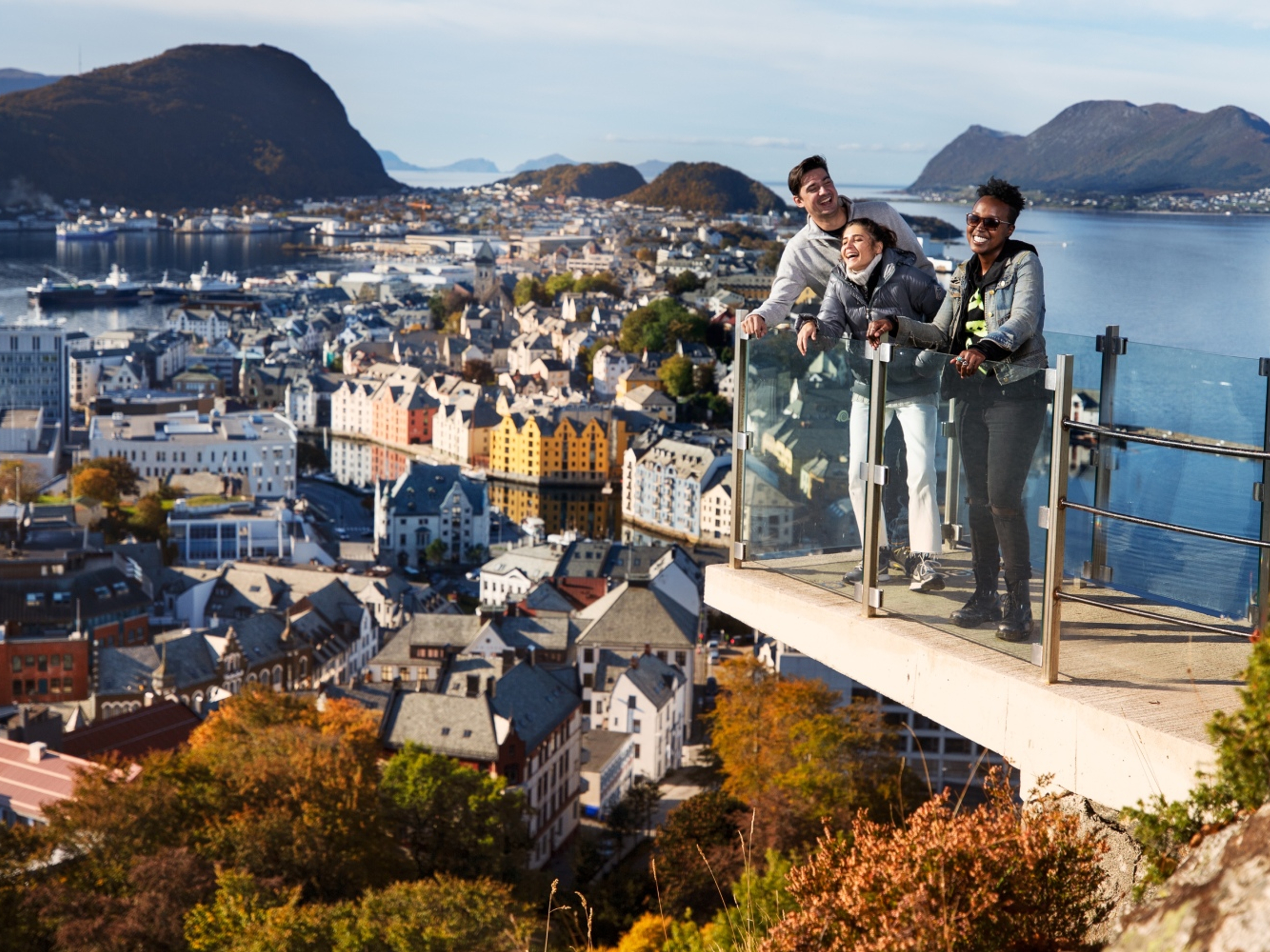Three people standing at a viewpoint above the city of Ålesund in Fjord Norway