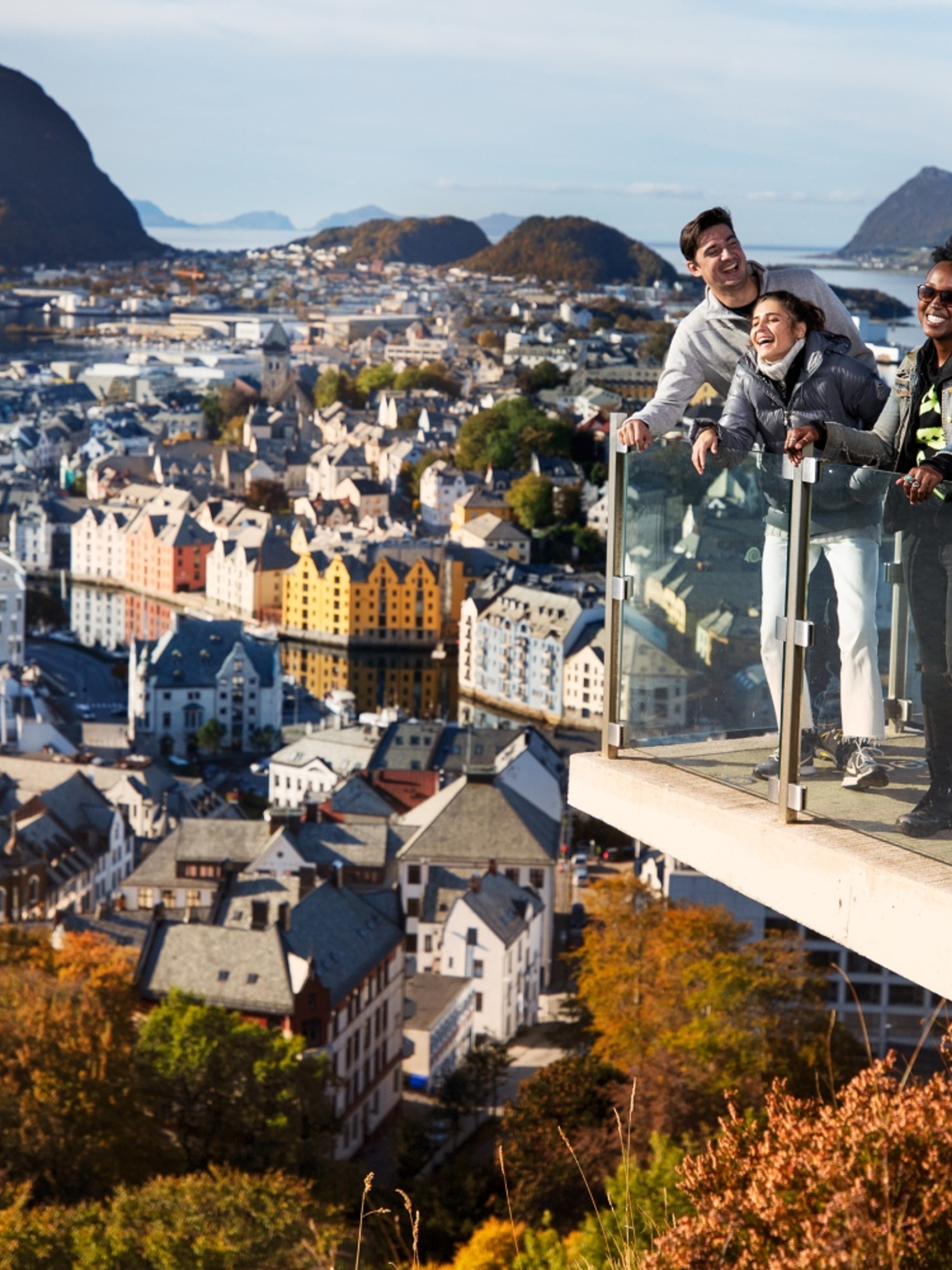 Three people standing at a viewpoint above the city of Ålesund in Fjord Norway