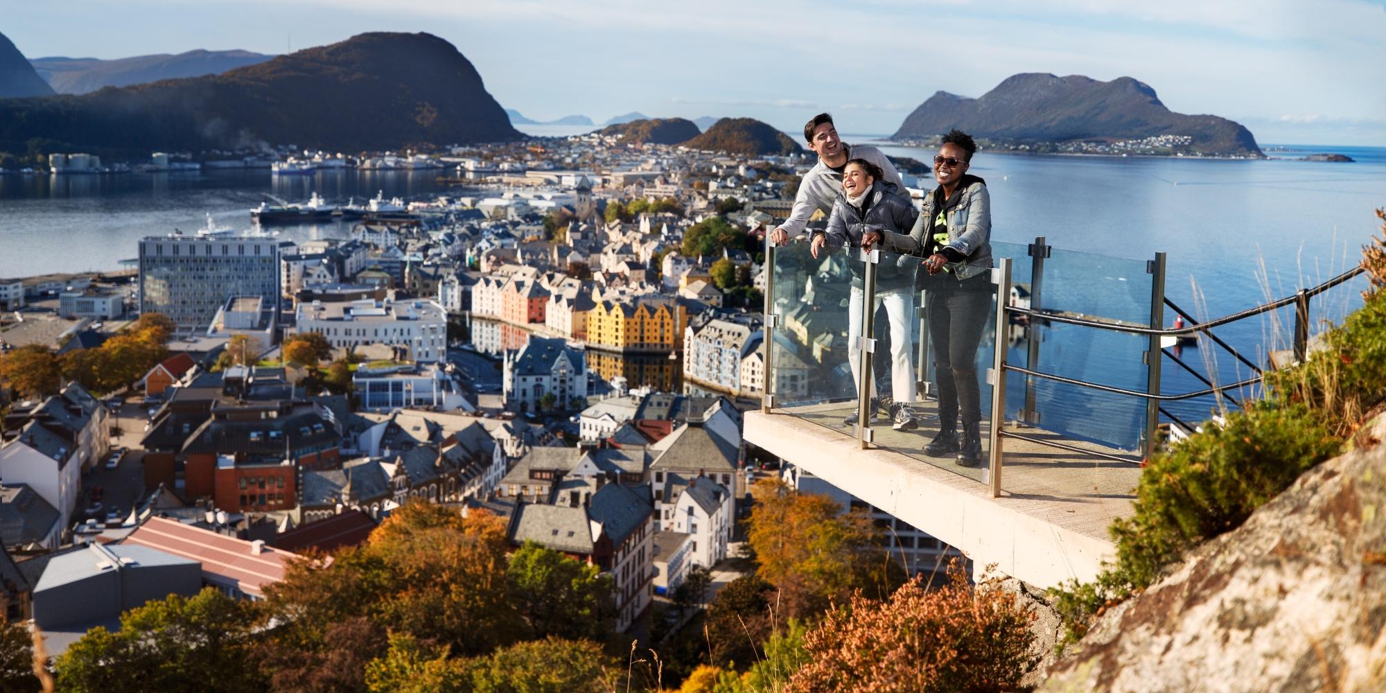 Three people standing at a viewpoint above the city of Ålesund in Fjord Norway