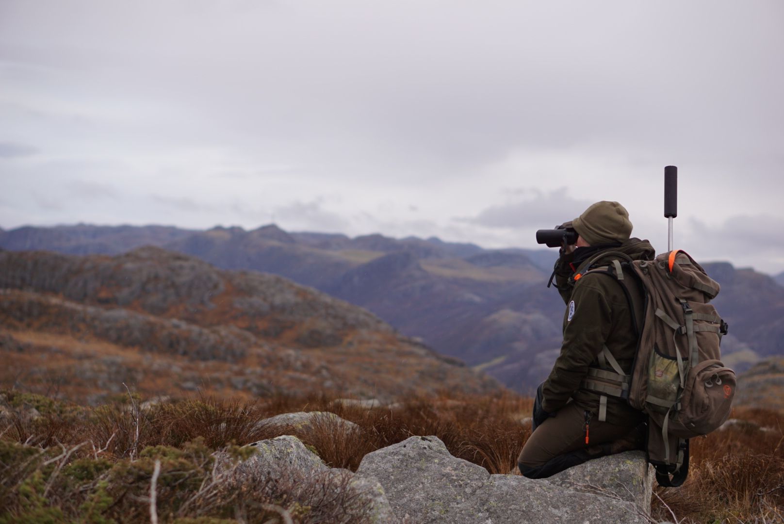 En mann ser ut over fjellene gjennom en kikkert
