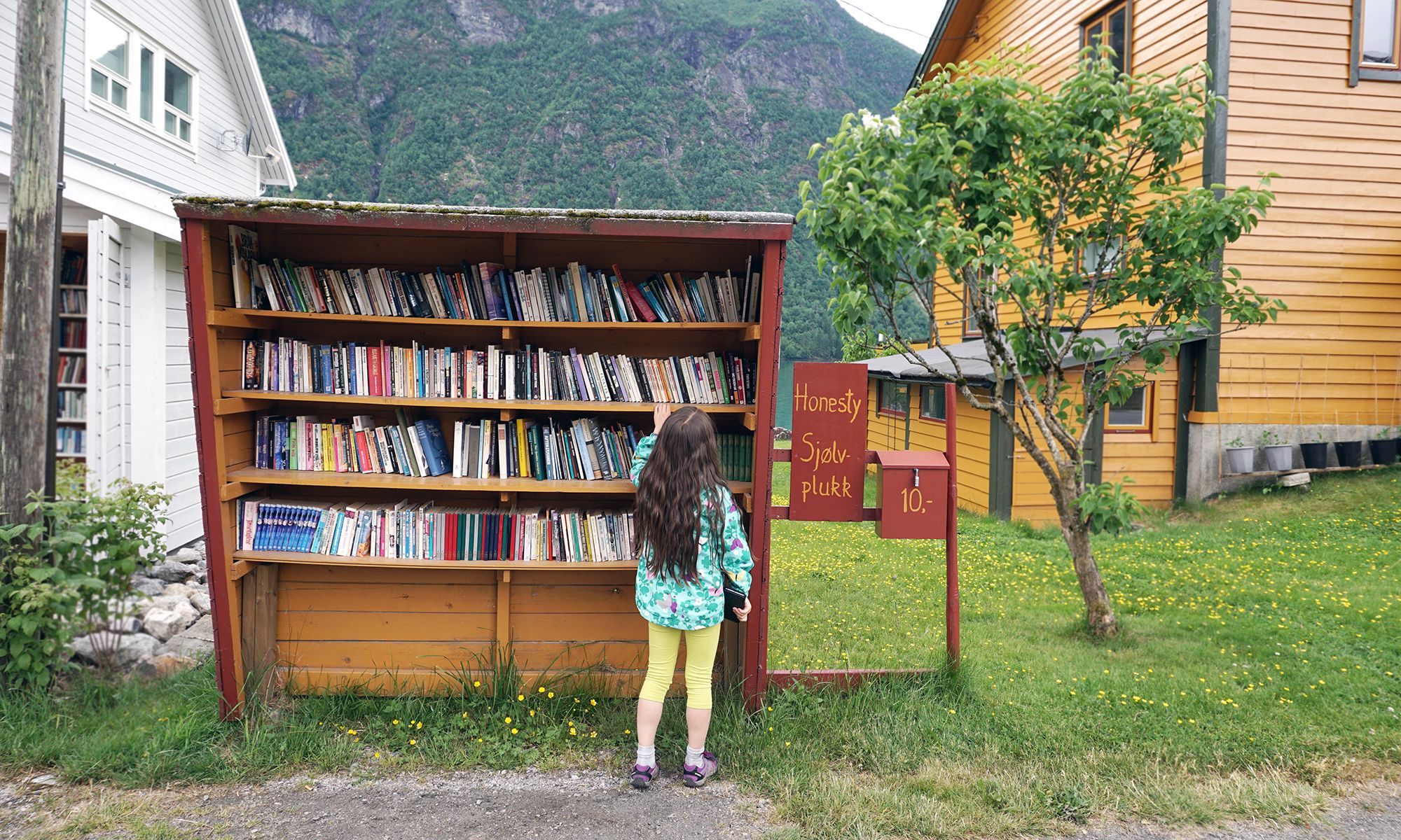 A girl is browsing books in the outdoor bookshop Sjølvplukk in The Norwegian book town in Fjærland, Sogn og Fjordane