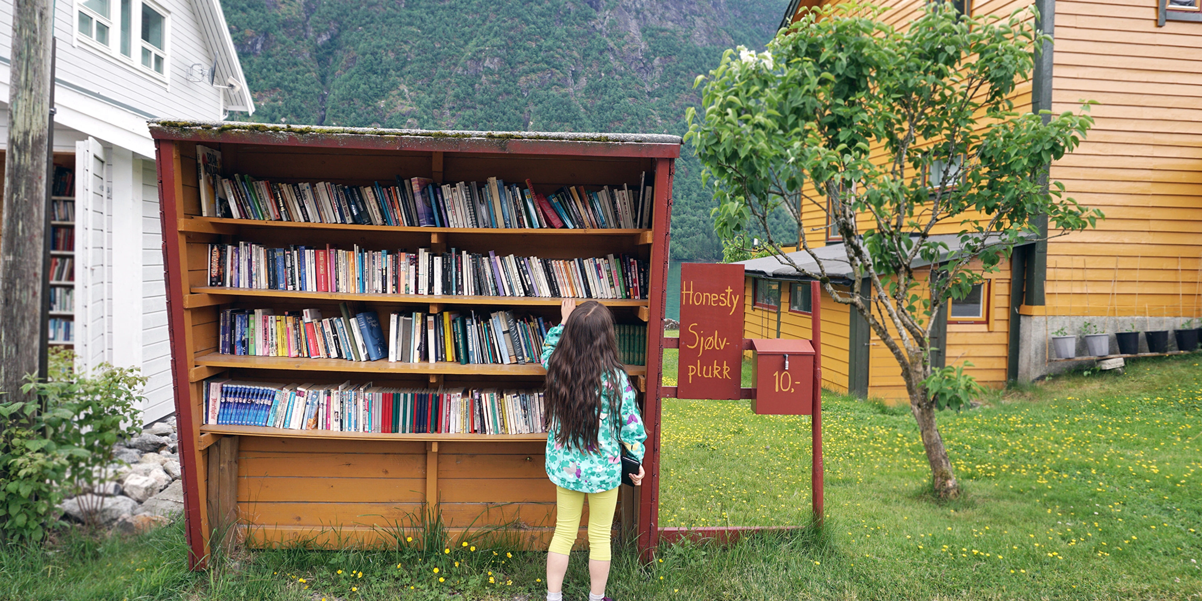 A girl is browsing books in the outdoor bookshop Sjølvplukk in The Norwegian book town in Fjærland, Sogn og Fjordane