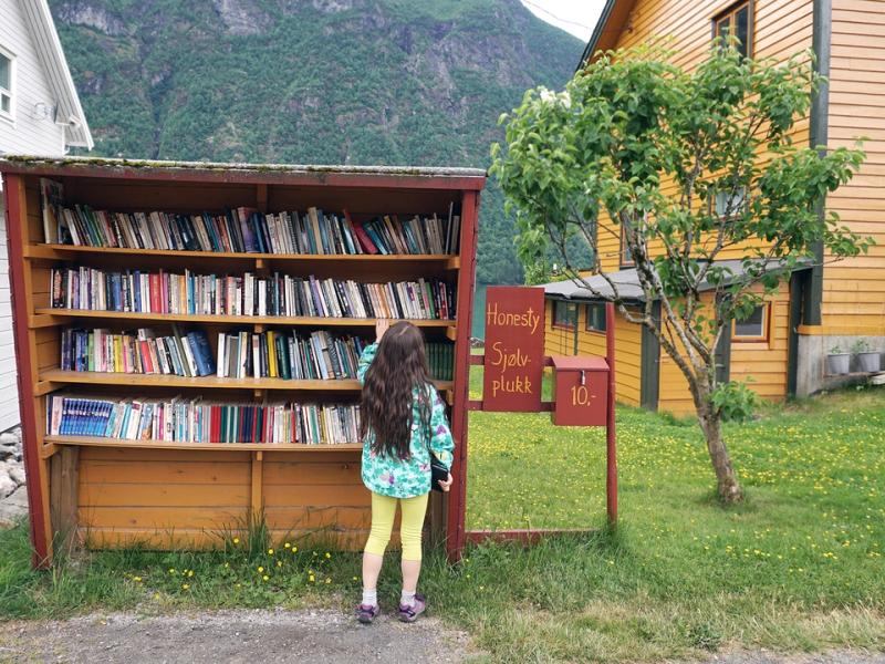 En jente ser på bøker i bokhandelen Sjølvplukk i Den norske bokbyen i Fjærland, Sogn og Fjordane
