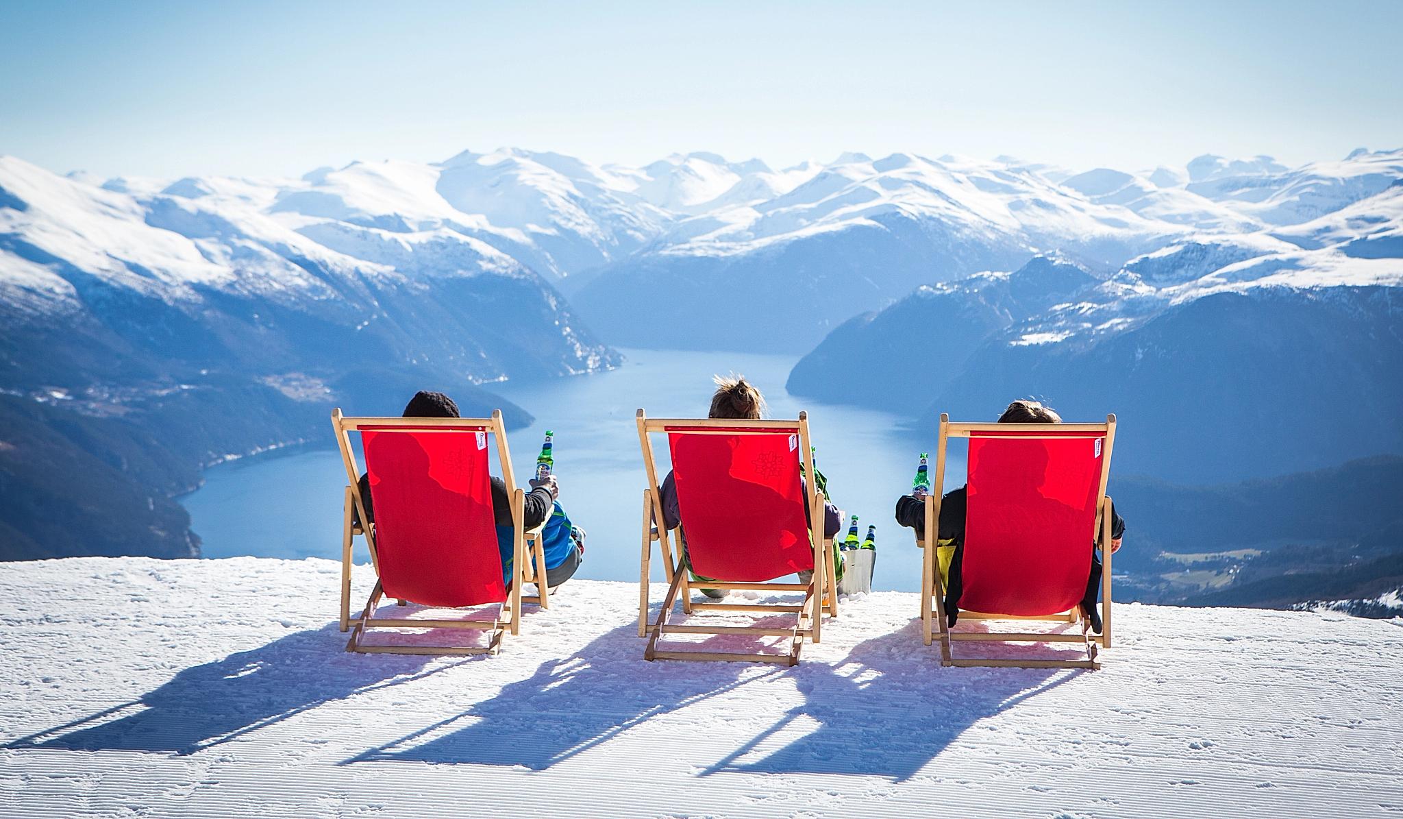 Tre personer i røde fluktstoler på toppen av slalåmbakken på Strandafjellet på Vestlandet