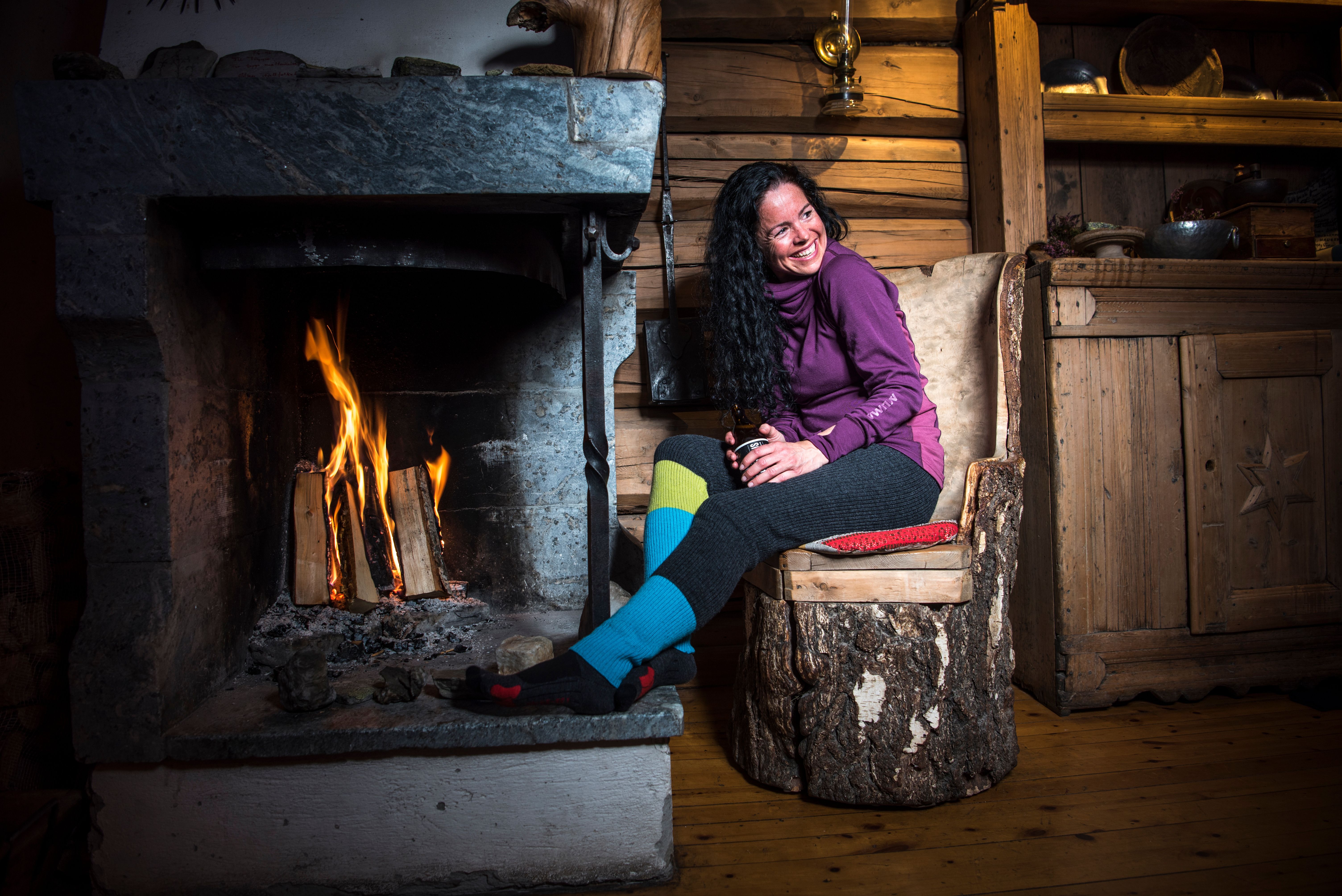 Woman relaxing in front of the fire place at the Smuksjøseter mountain cabin at Høvringen, Eastern Norway