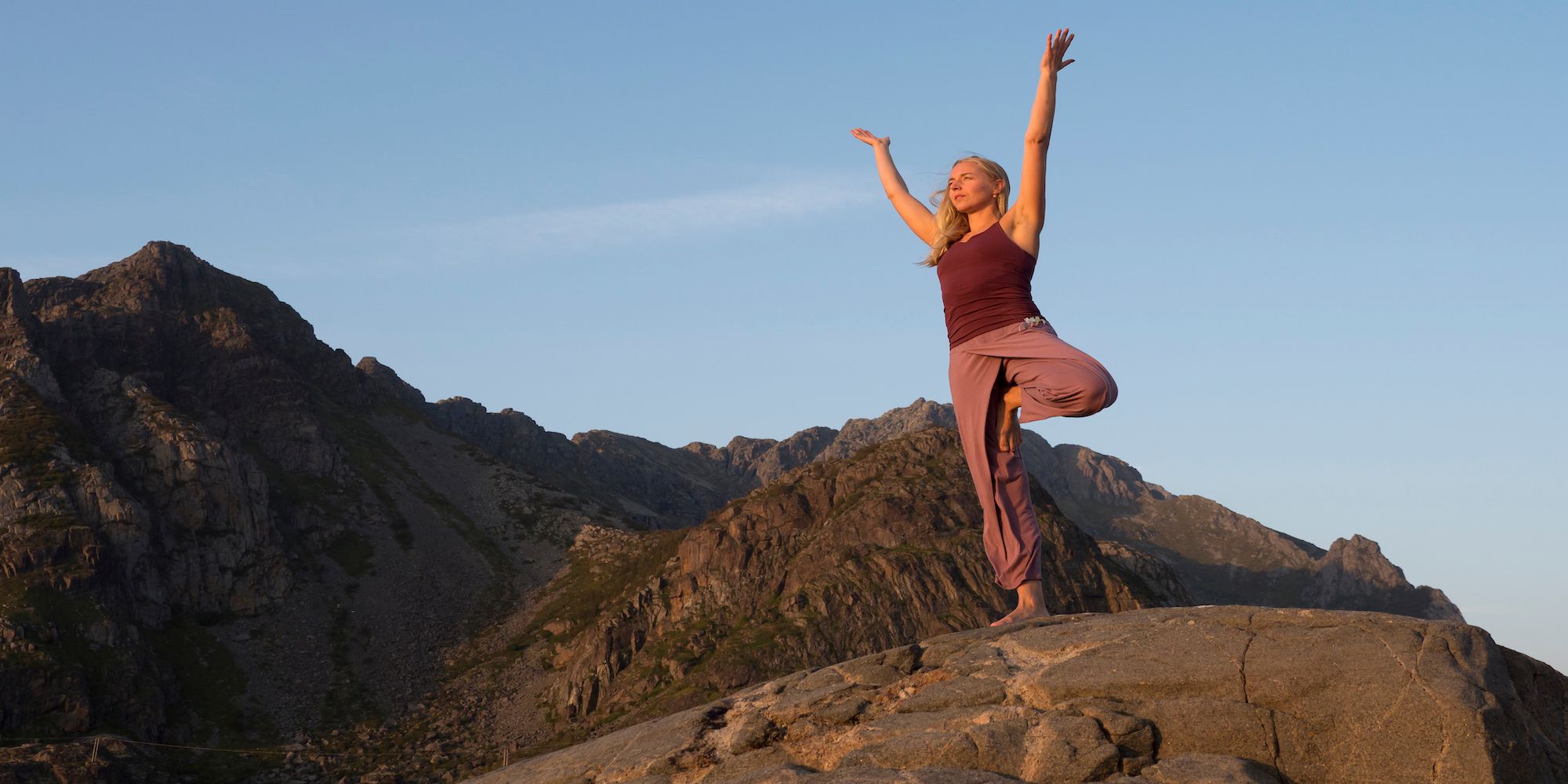 A woman doing yoga while on a hike in Lofoten, Northern Norway