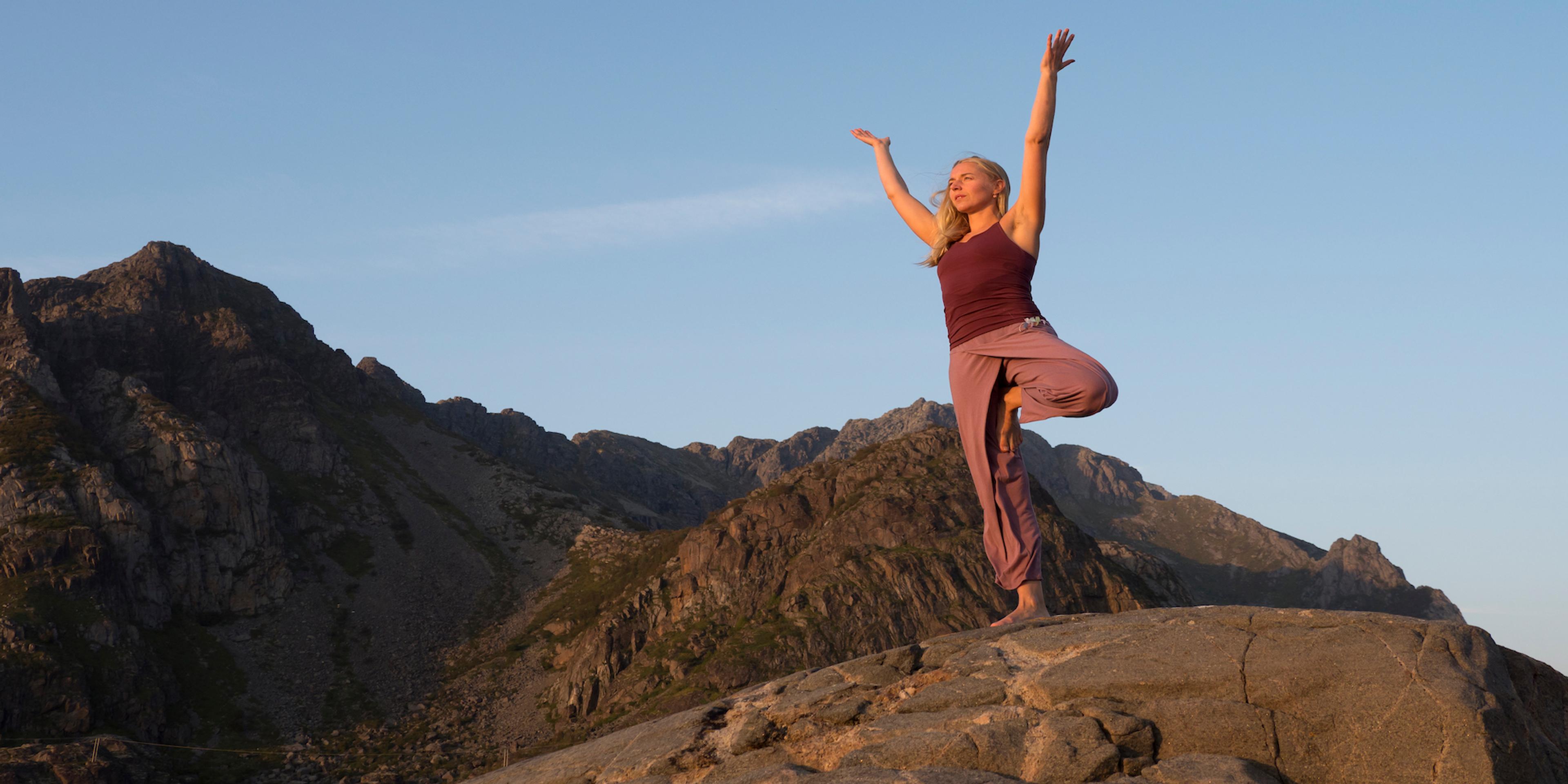 A woman doing yoga while on a hike in Lofoten, Northern Norway