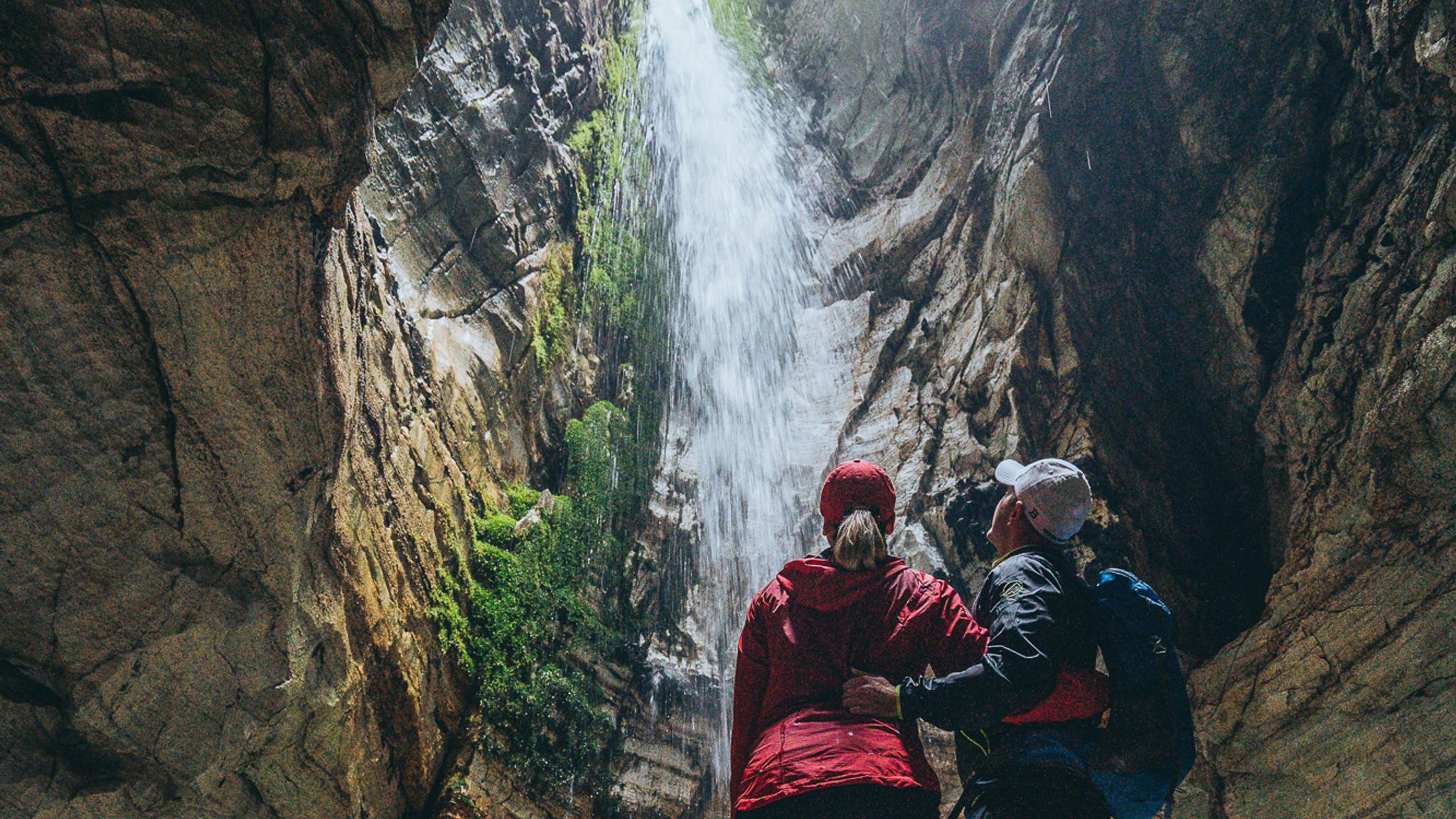 two people watching a waterfall inside Trollkirka