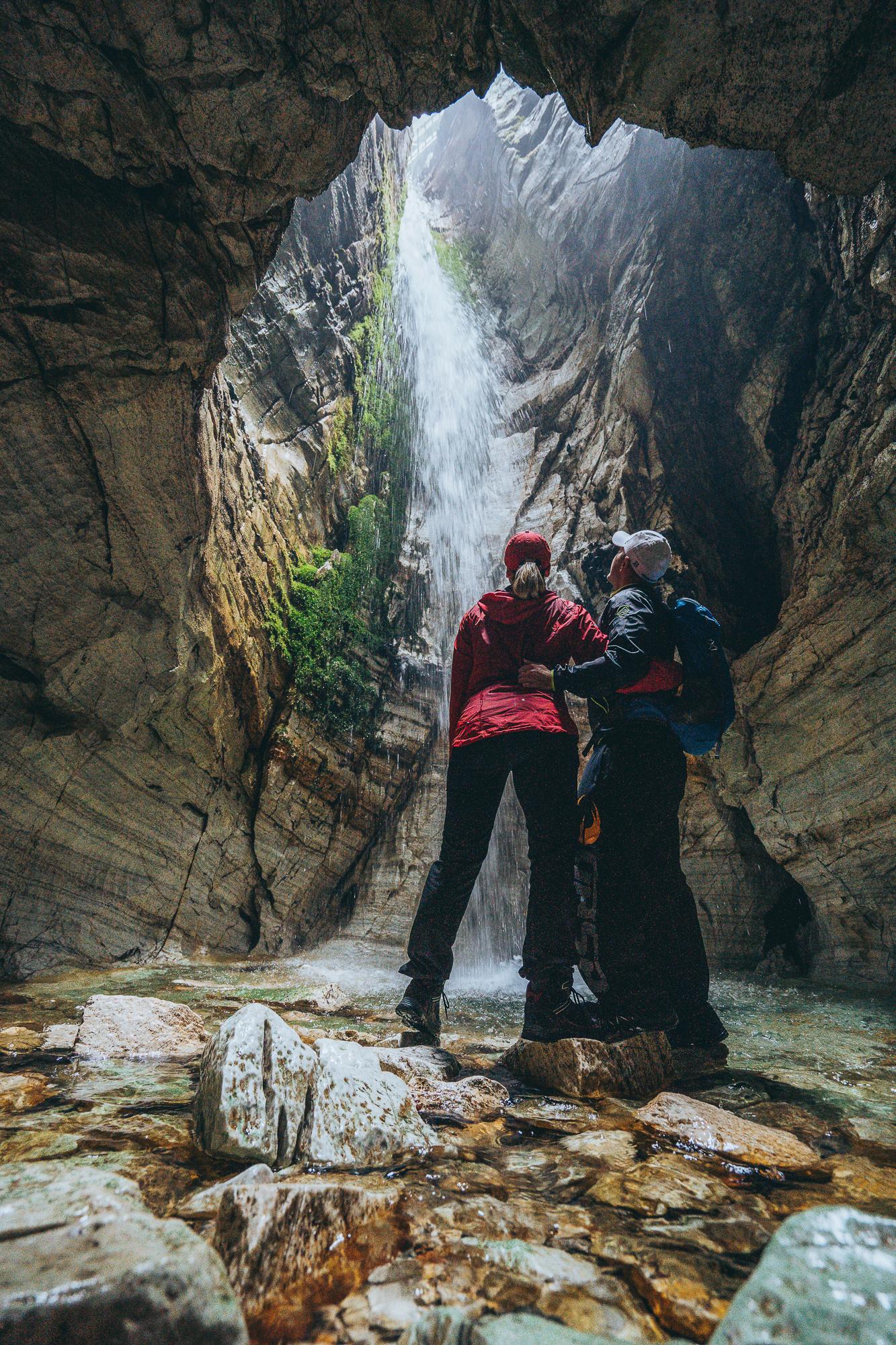 two people watching a waterfall inside Trollkirka