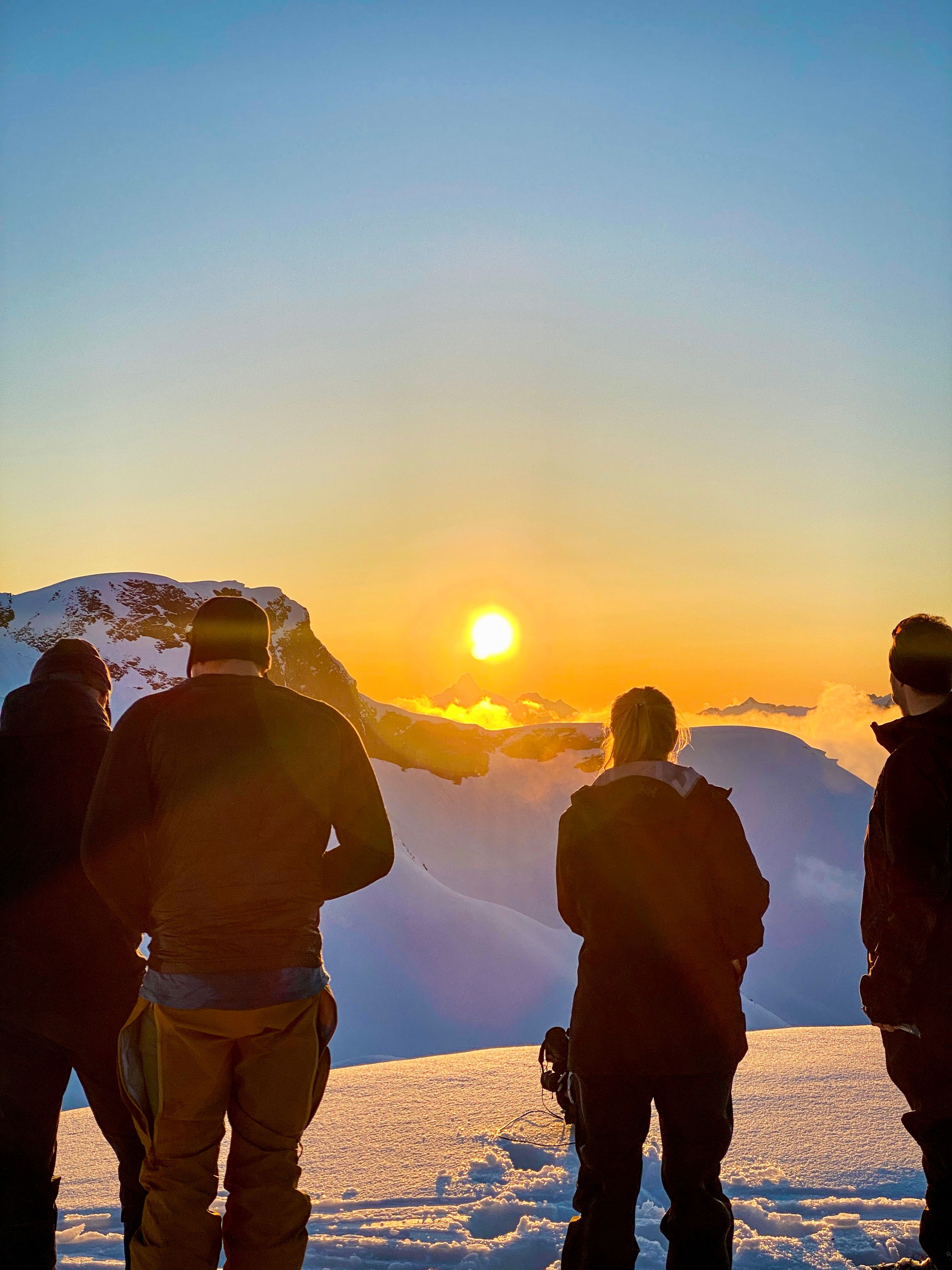 People on the snow covered mountain watching the sunset in Ørsta, Fjord Norway