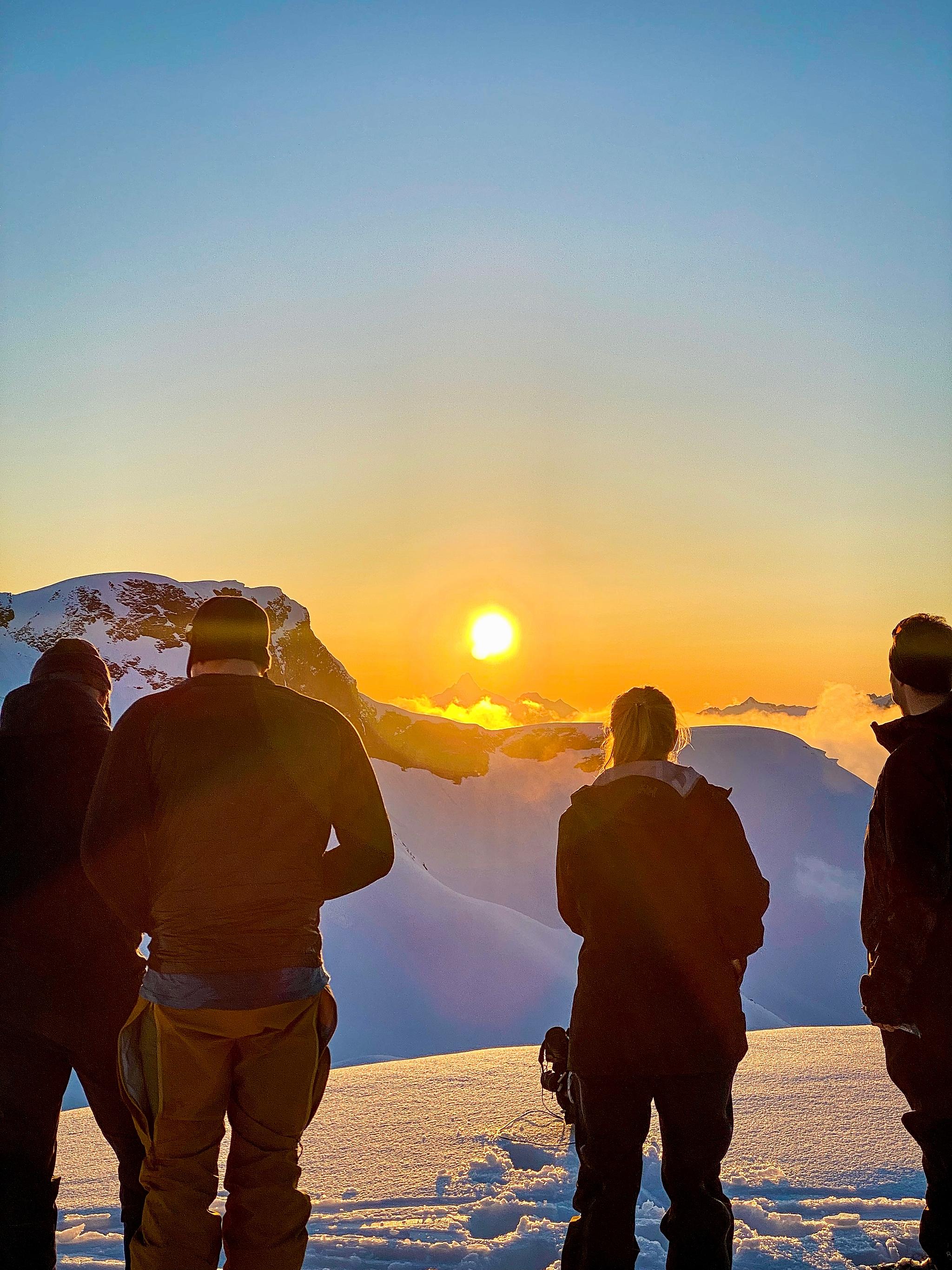 People on the snow covered mountain watching the sunset in Ørsta, Fjord Norway