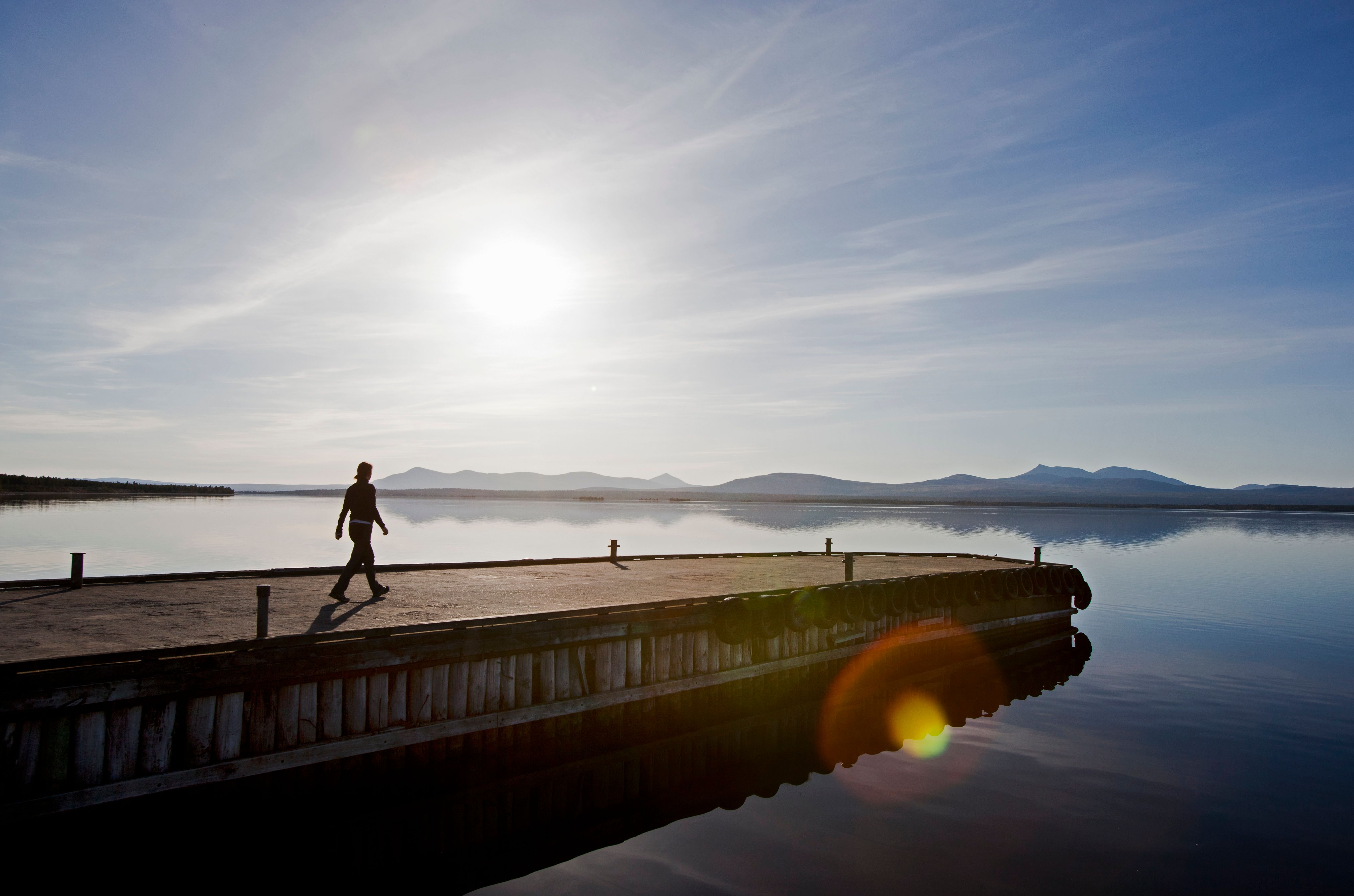 A person walking on a floating dock on a lake.