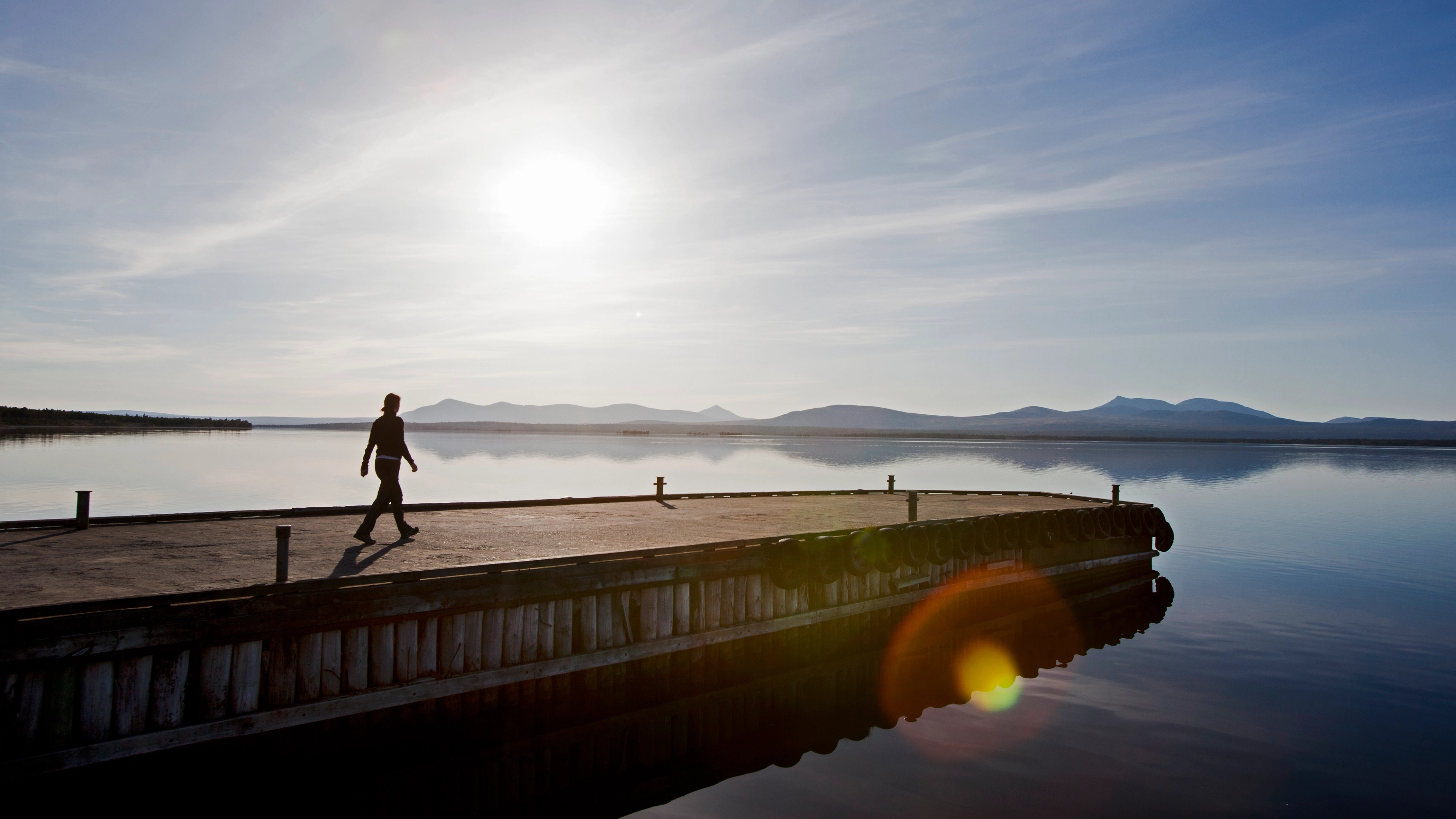 A person walking on a floating dock on a lake.