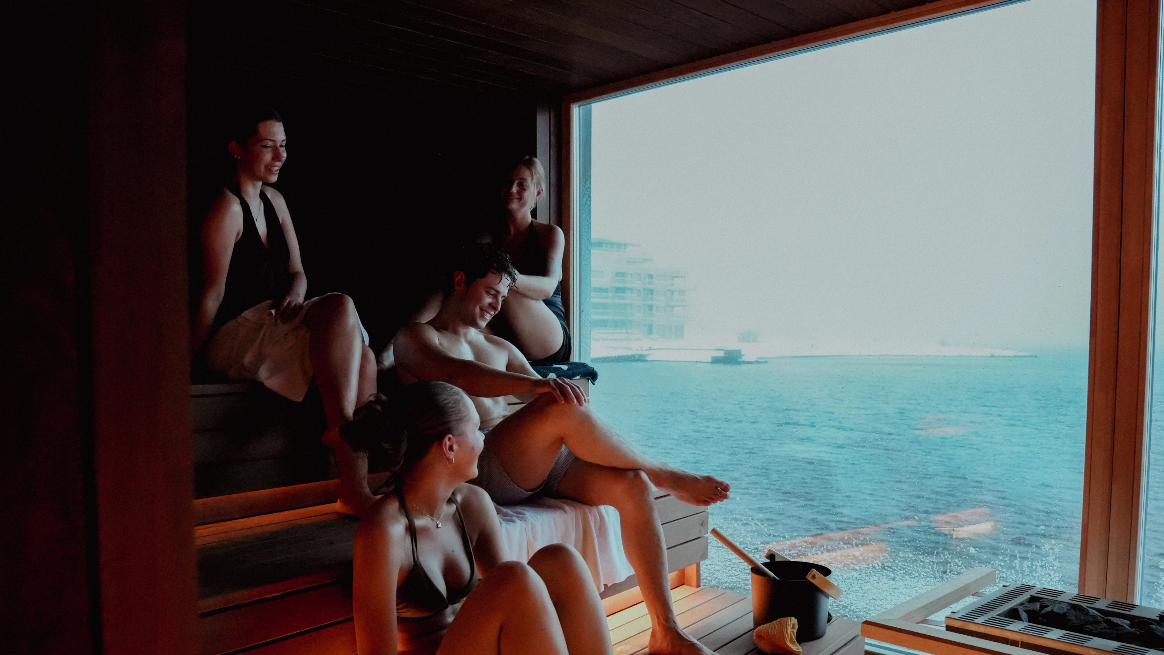 A group of friends sitting inside the sauna at Smeigedag Sauna, Bystranda in Kristiansand