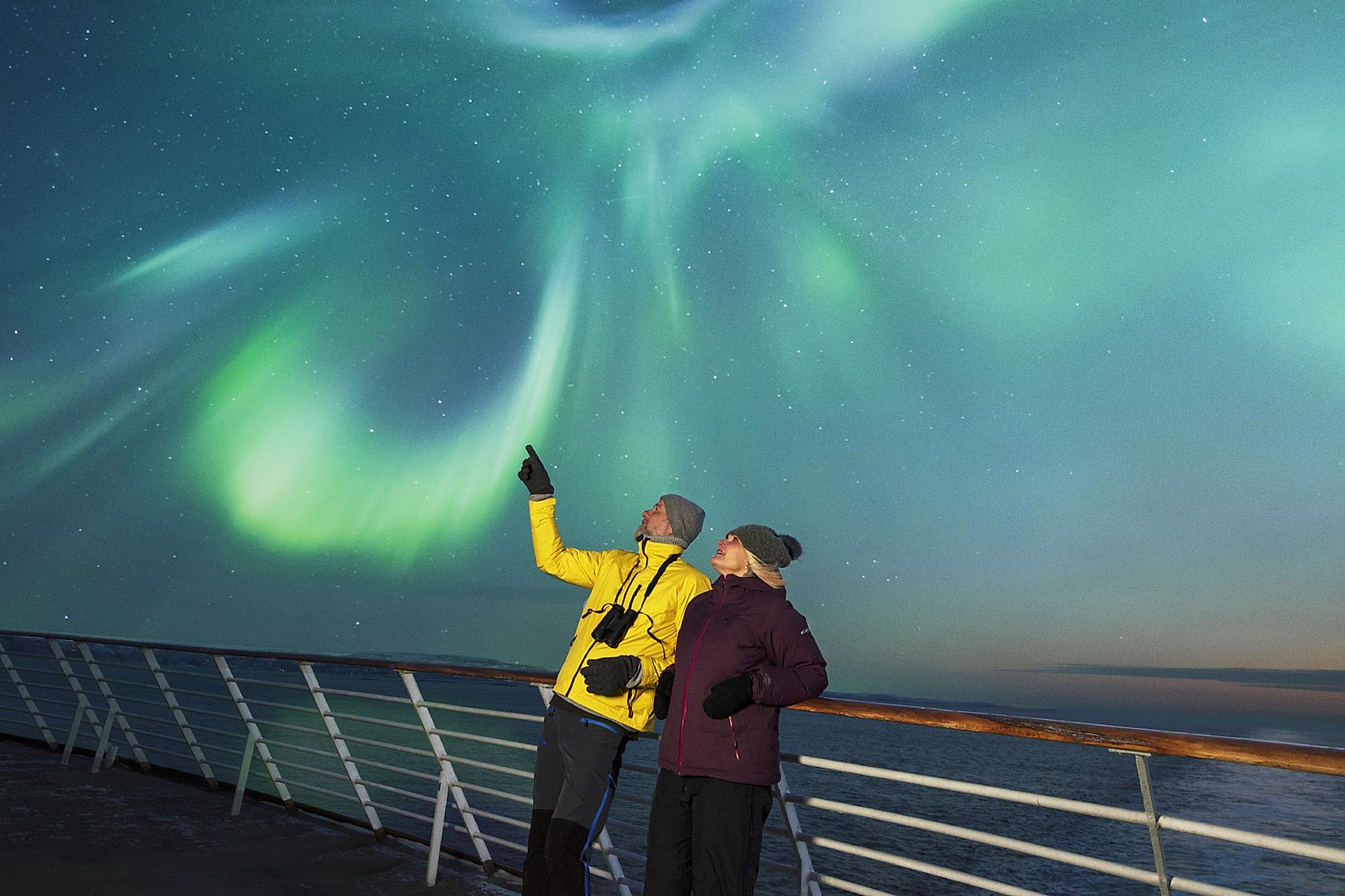 Couple watching the northern lights from deck at Hurtigruten