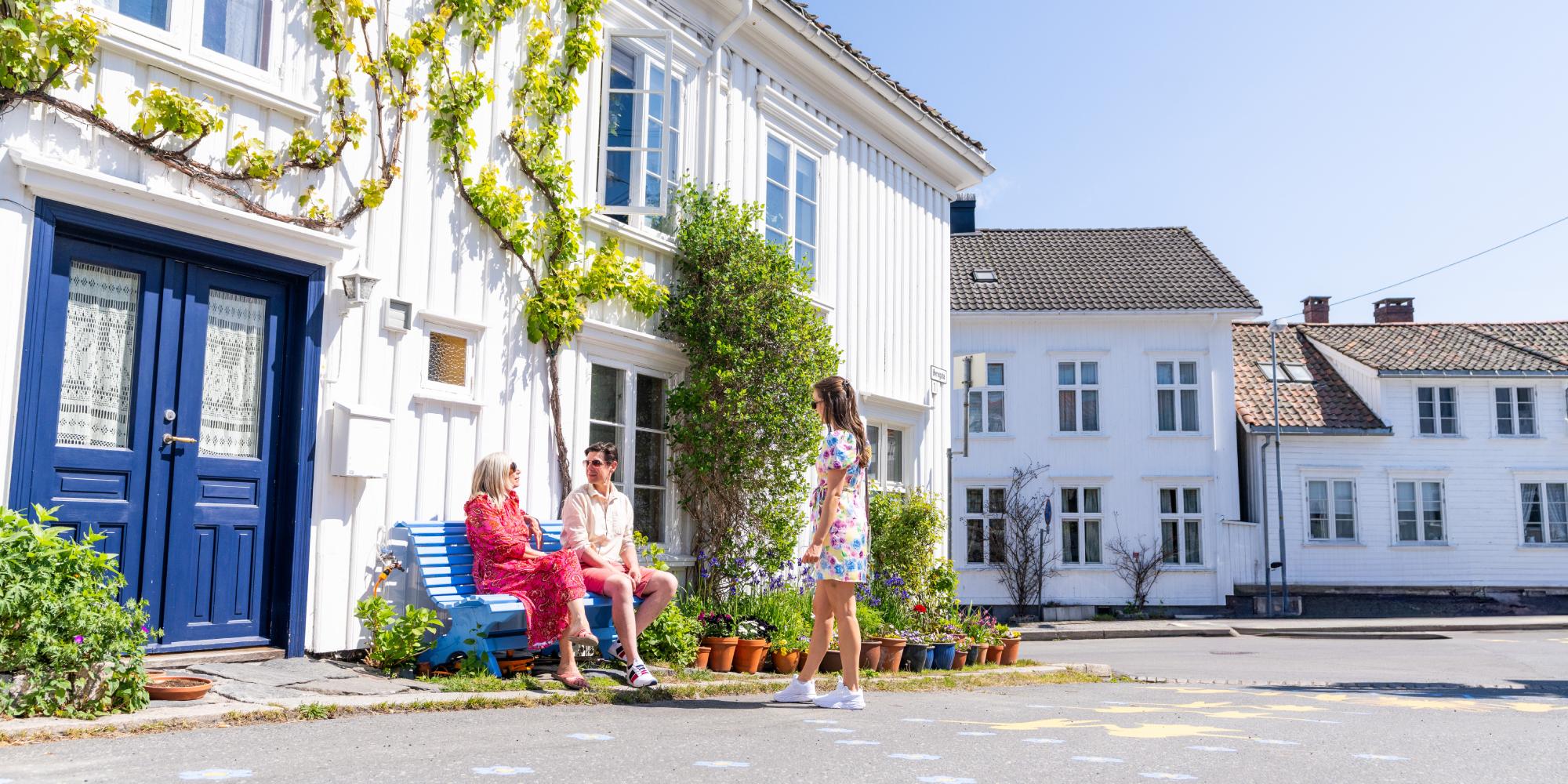 People sitting in front of white house in Risør, Southern Norway