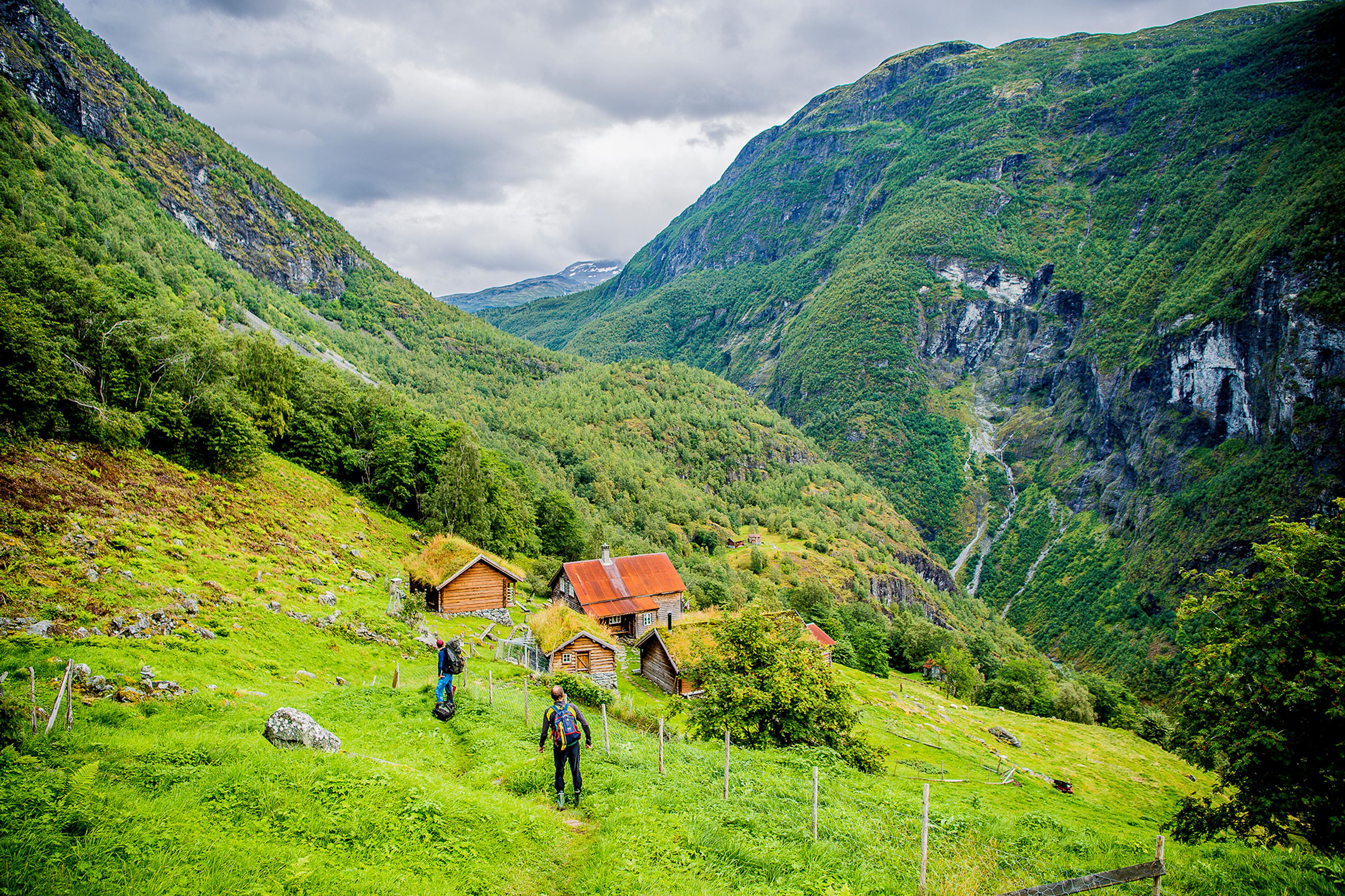 Två personer går mot fjällgården Avdalen i Utladalen, Fjord Norge