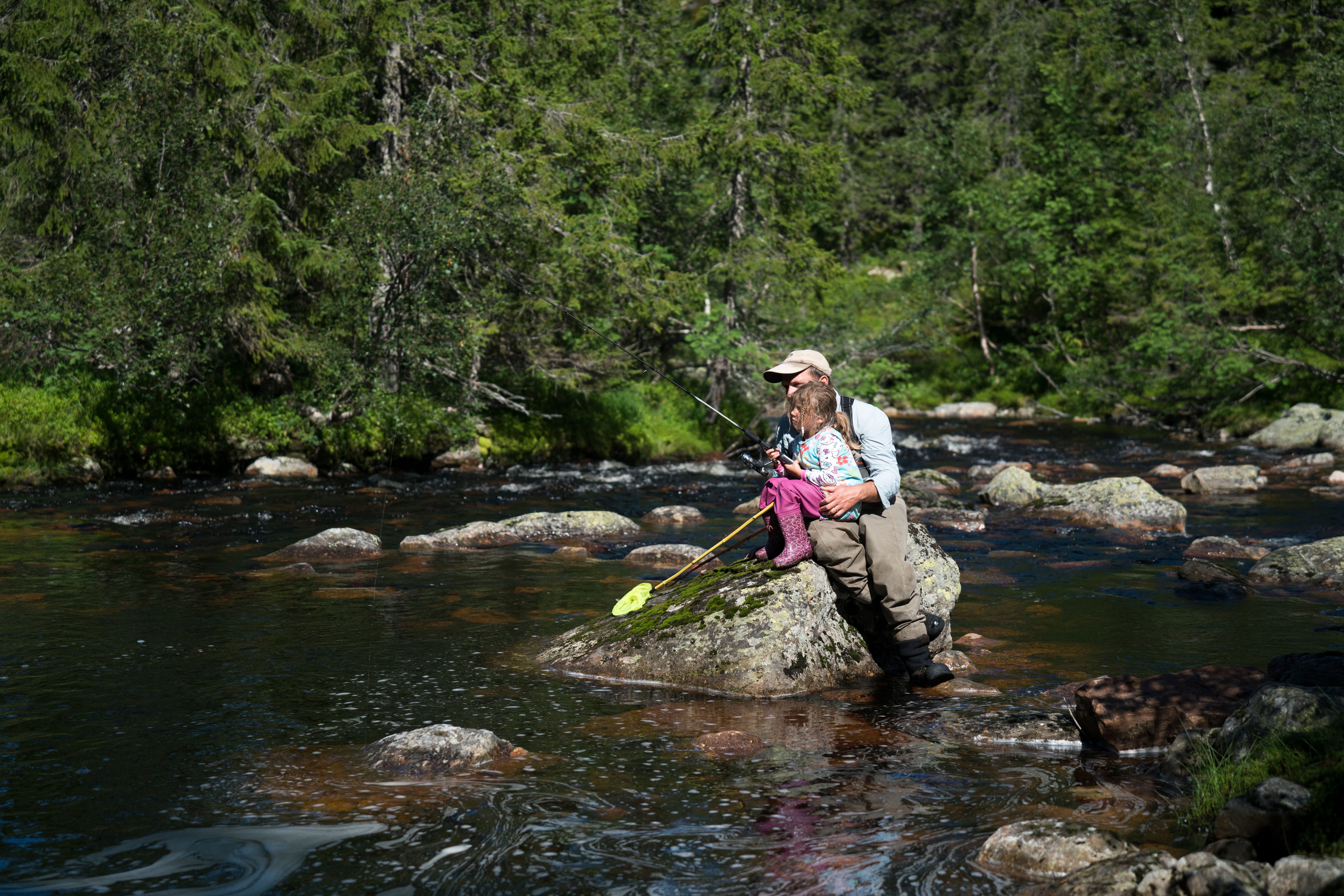 Ein Vater hilft seiner Tochter beim Angeln in einem Fluss in Blefjell, Ostnorwegen.