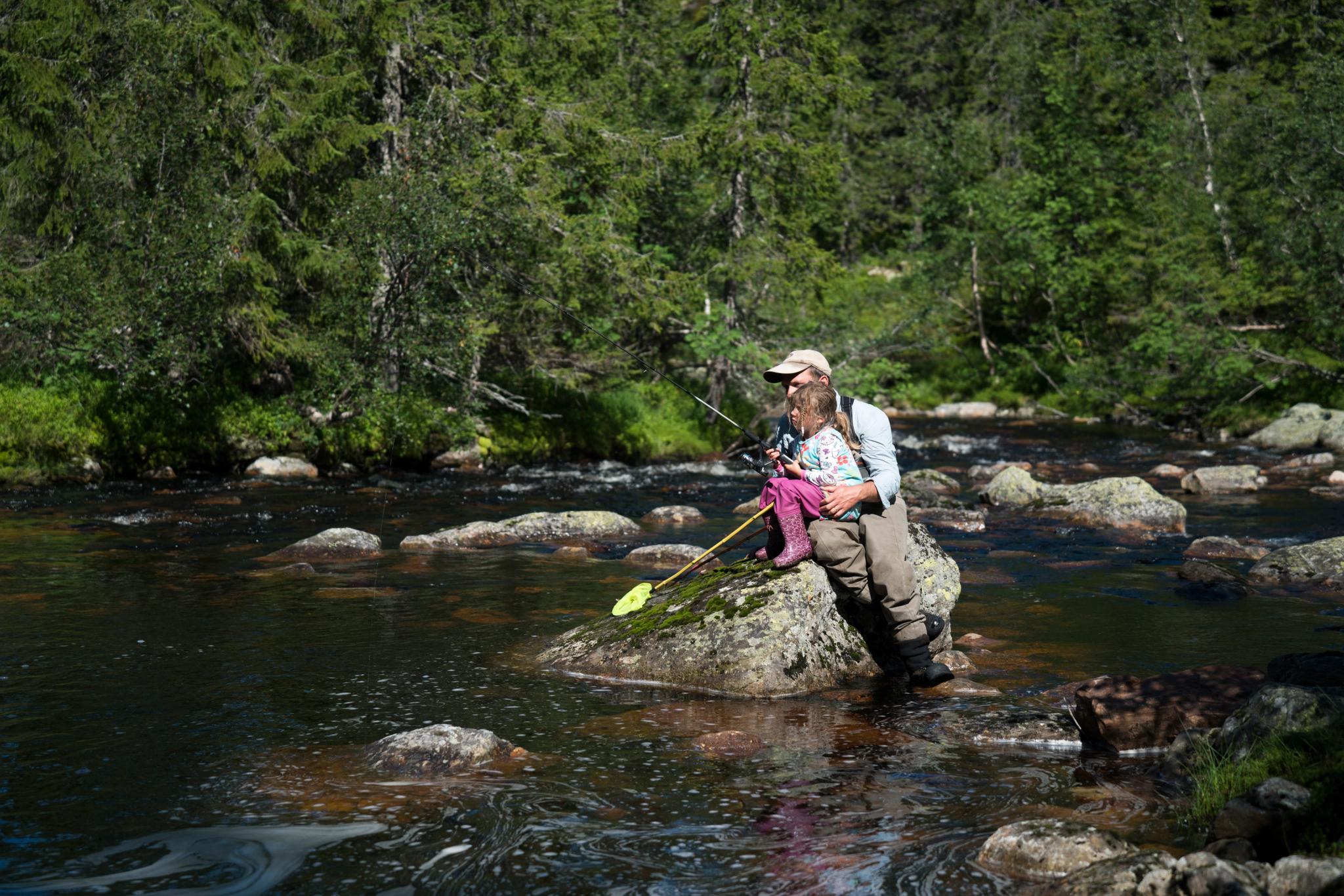 A father helps his daughter to fish in a river in Blefjell, Eastern Norway