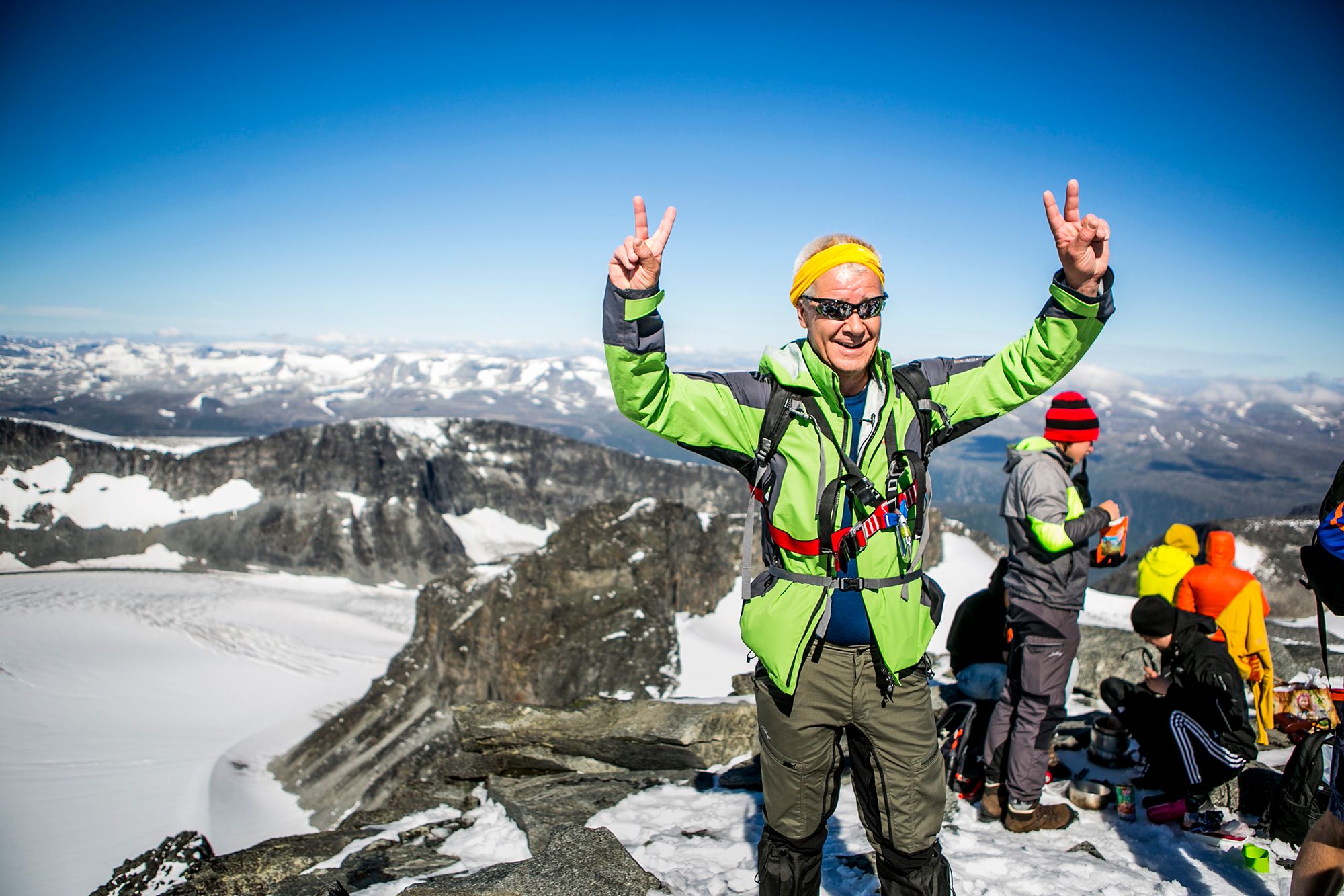 A man raises his hands in the air happy to have rached the top of Galdhøpiggen in Jotunheimen