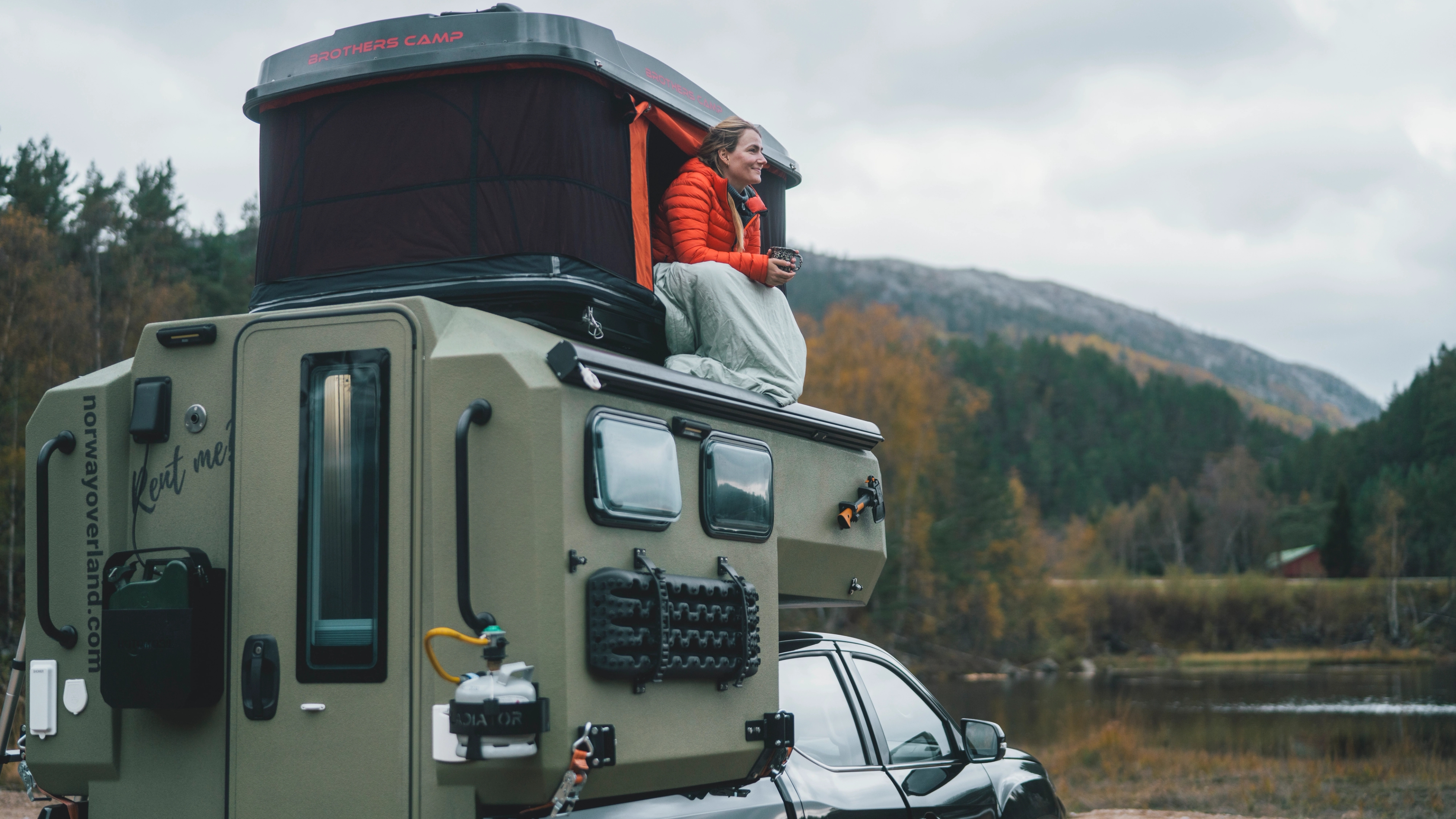 A woman taking in the stunning views from the tent atop her electric overlander in Southern Norway.