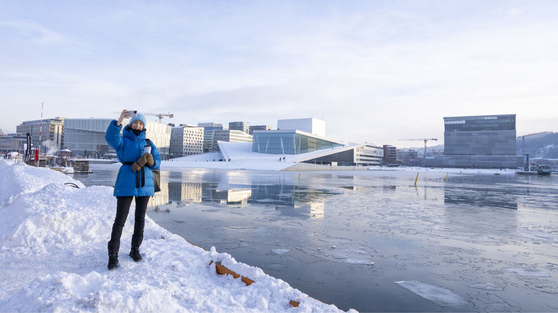 Woman taking selfie in front of Deichman Bjørvika, The Norwegian Opera and Ballet and MUNCH
