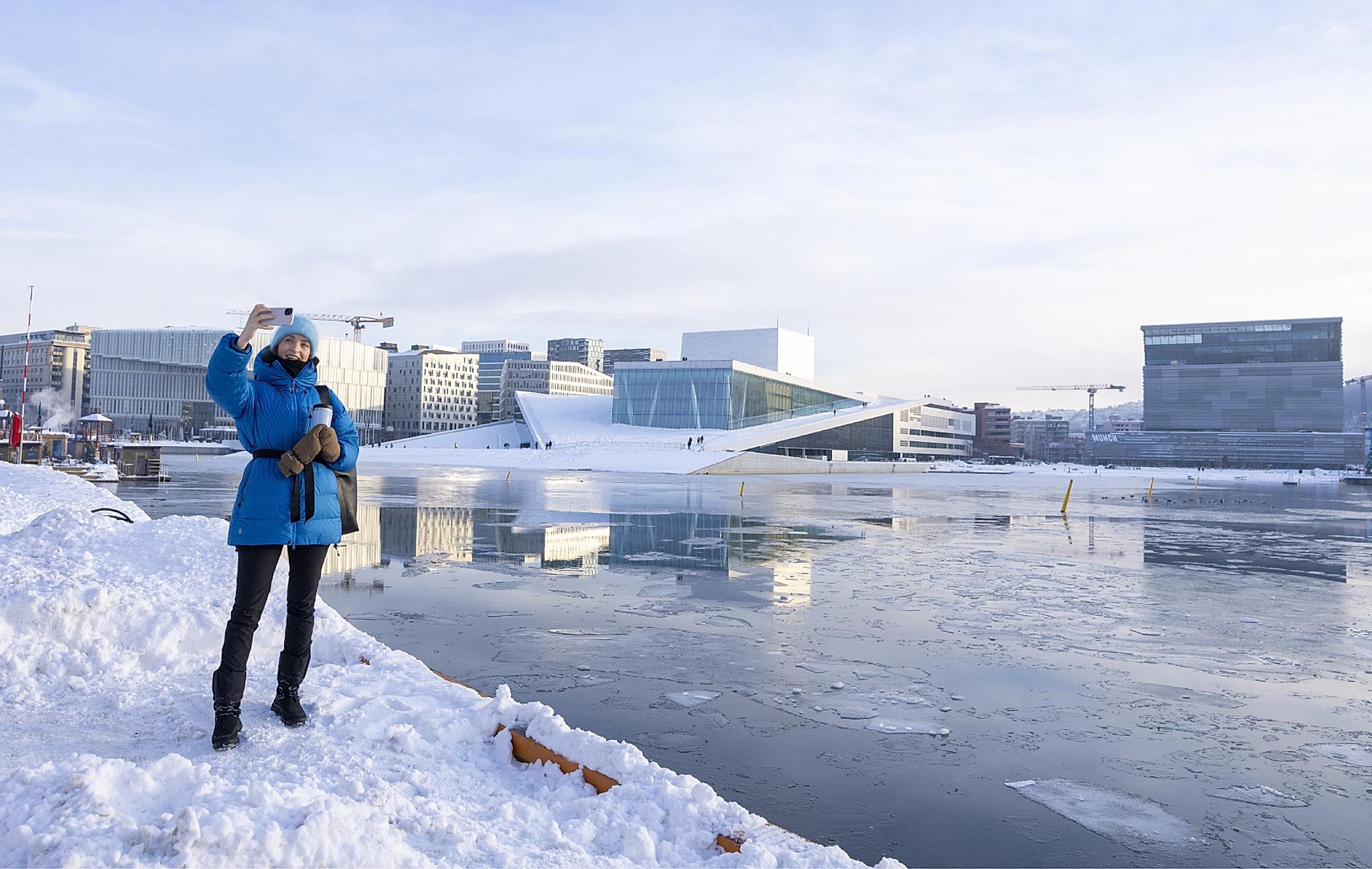 Woman taking selfie in front of Deichman Bjørvika, The Norwegian Opera and Ballet and MUNCH