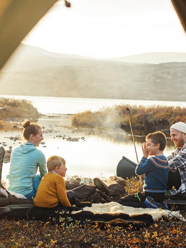 Family on four sitting by the campfire beside the tent in Oppdal, Trøndelag