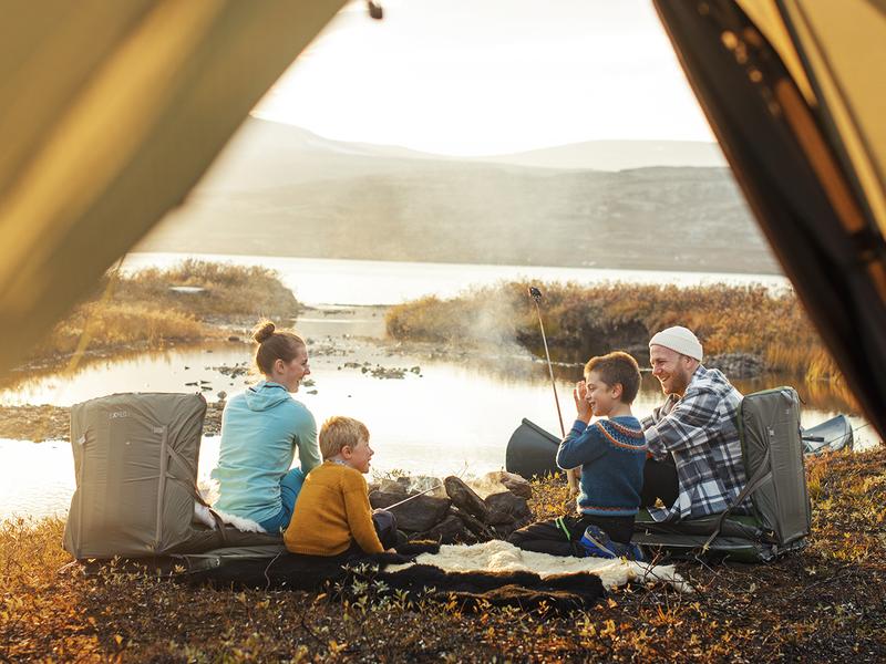 Family on four sitting by the campfire beside the tent in Oppdal, Trøndelag
