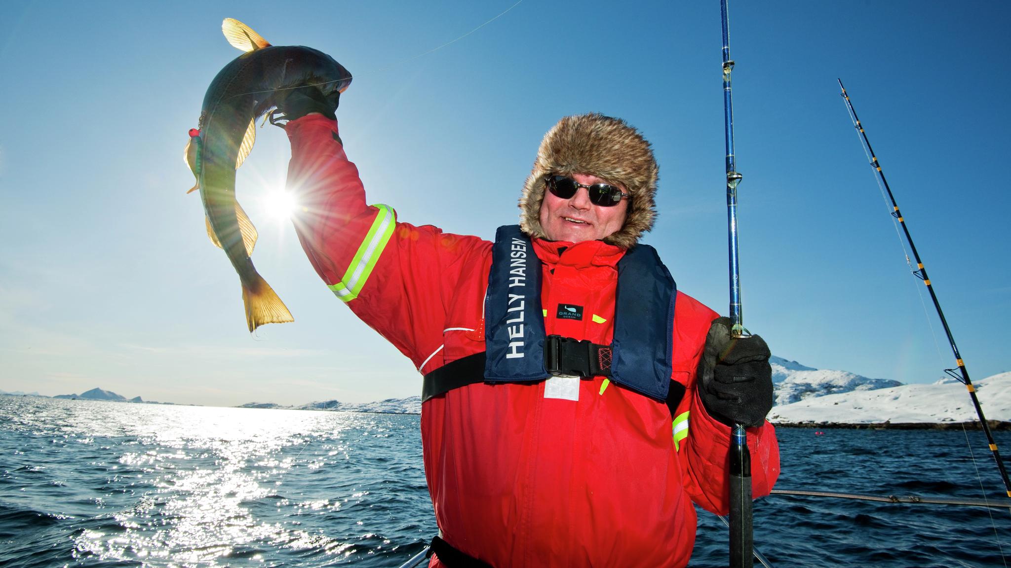 A man who has caught a fish in Austnesfjorden in Lofoten in Northern Norway