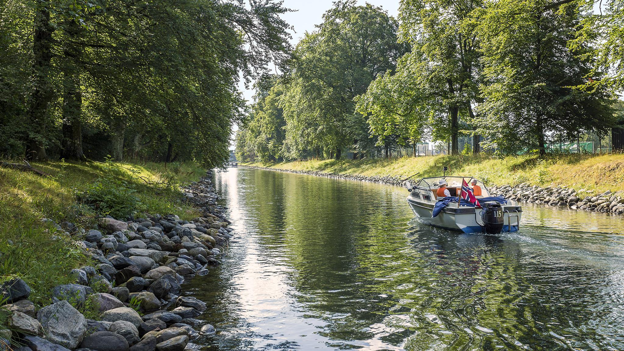 En båt kjører i rolig fart gjennom Horten i Vestfold en sommerdag