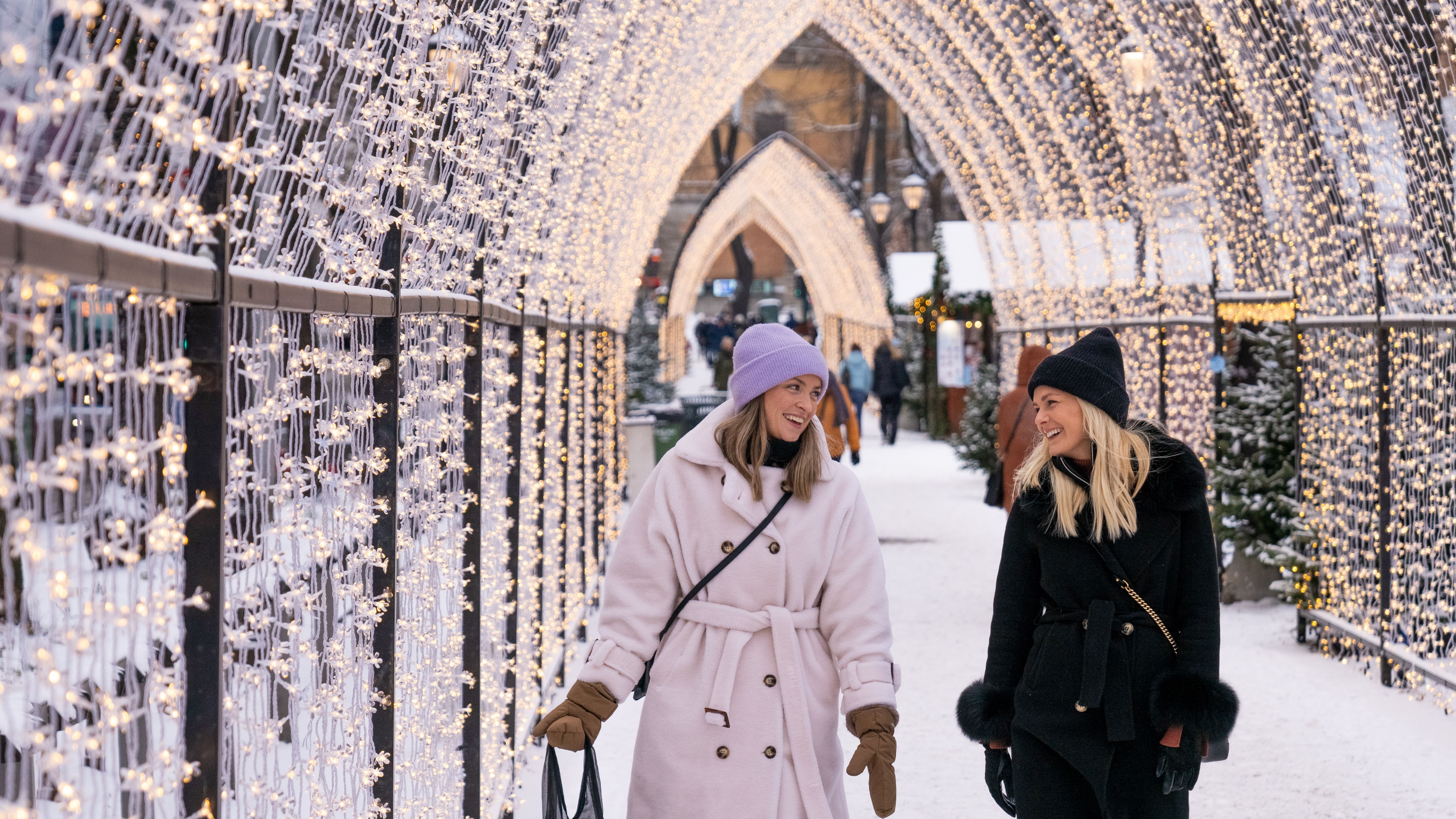 Two women walking through the lit Christmas market in Oslo, Eastern Norway